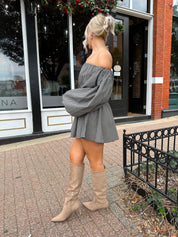 Woman wearing black checkered puff sleeve off the shoulder mini dress. 