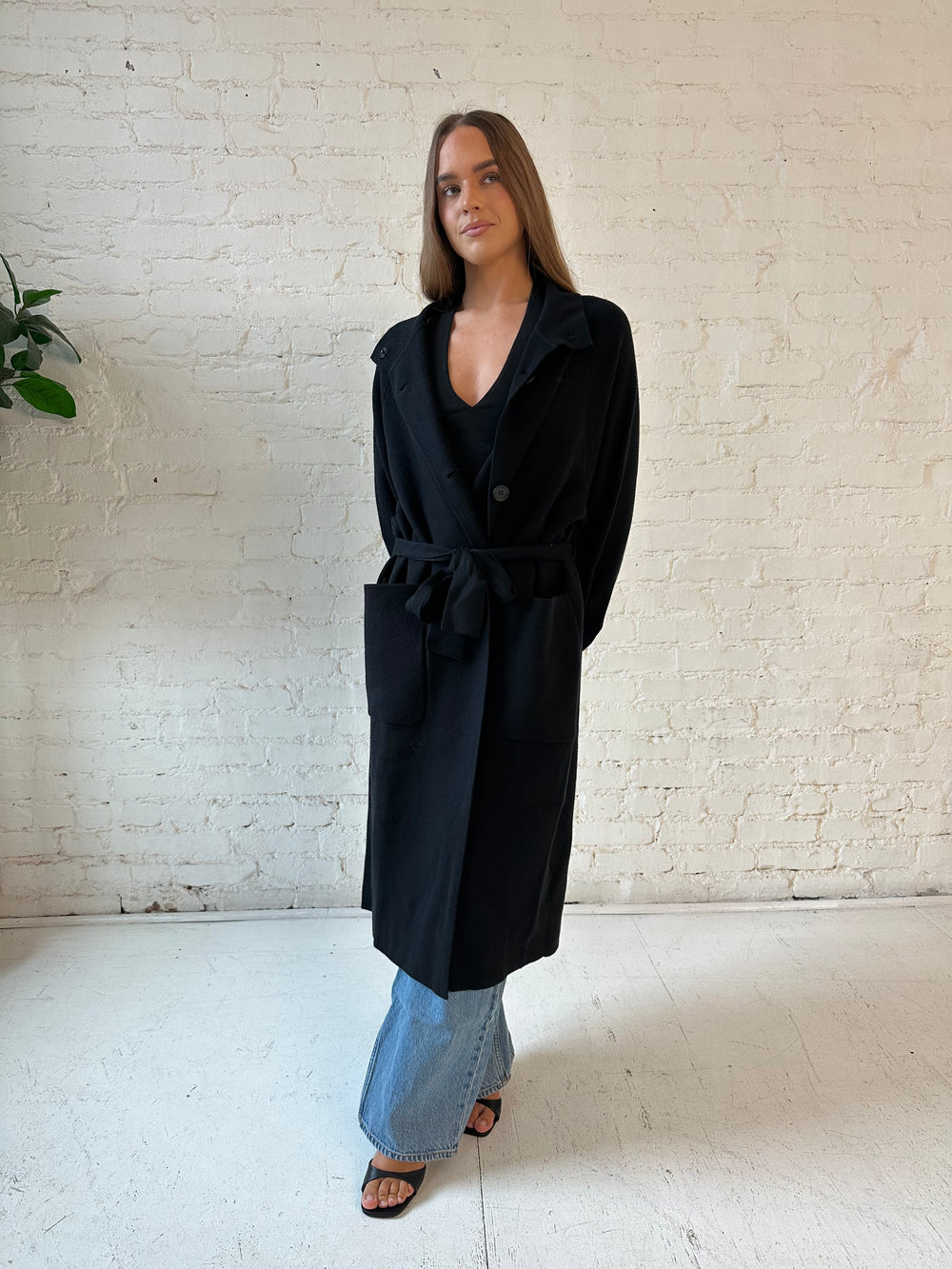 Woman wearing black heavy knit belted duster cardigan with medium wash jean. 