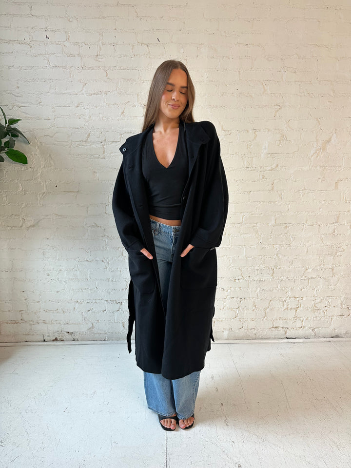 Woman wearing black heavy knit belted duster cardigan with medium wash jean. 