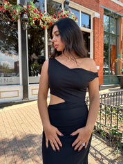 Woman wearing black mesh maxi dress with side cutout, and off the shoulder asymmetrical neckline. 