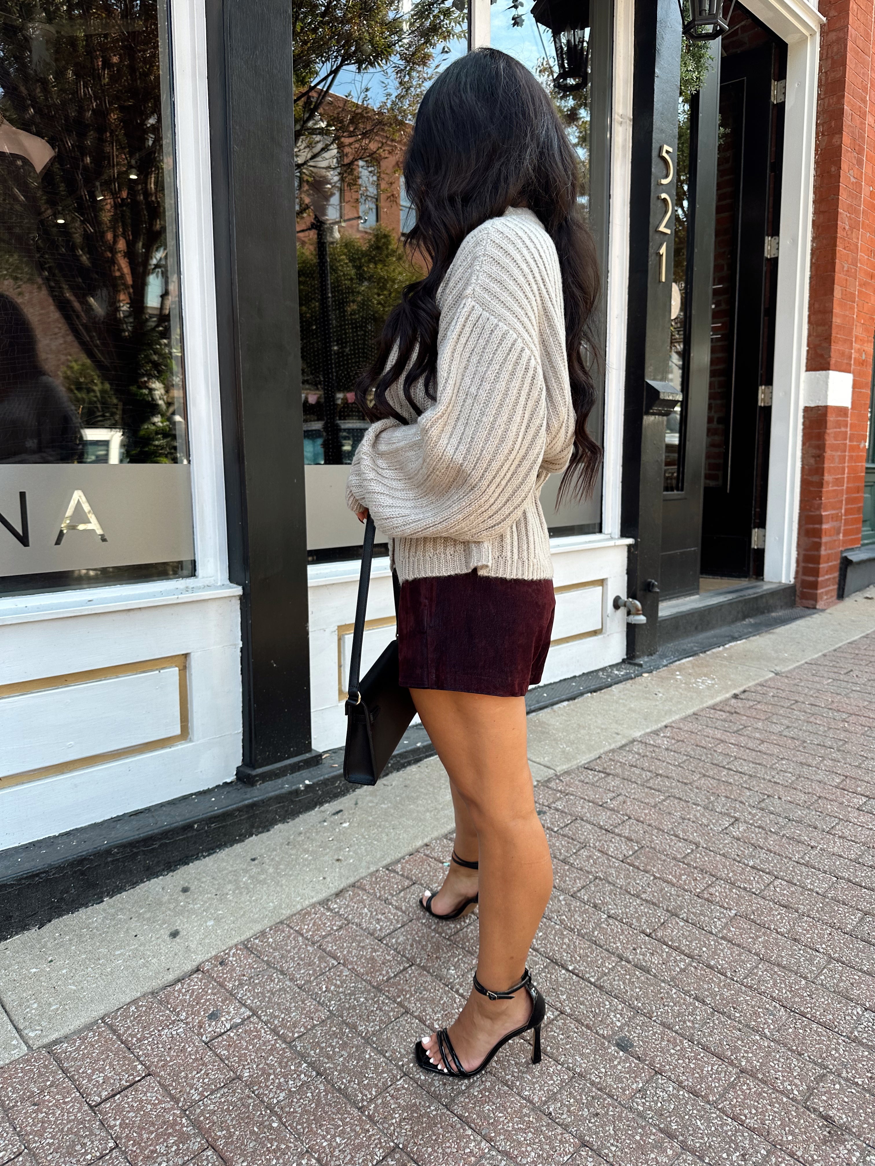 Woman wearing grey knit wrap cardigan with black belted waist. 