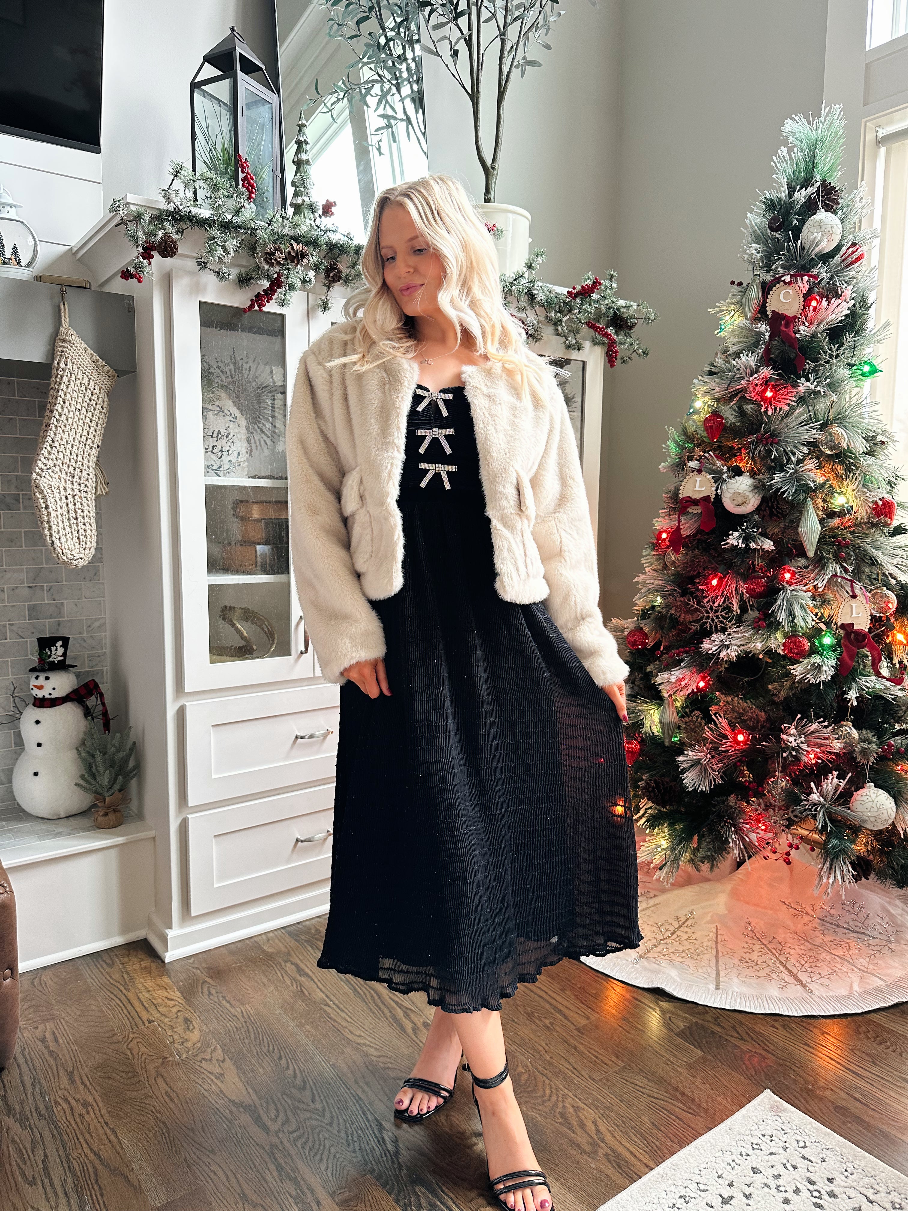 Woman wearing beige faux fur coat with front pockets and clasp closure. 