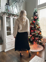 Woman wearing beige faux fur coat with front pockets and clasp closure. 