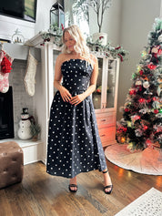 Woman wearing strapless black and white polka dot fit to flare midi dress. 