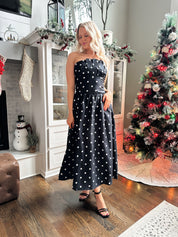 Woman wearing strapless black and white polka dot fit to flare midi dress. 
