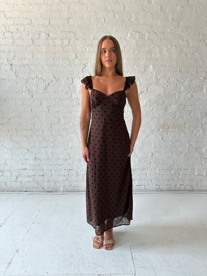 Woman wearing brown polka dot midi dress with ruffle straps.