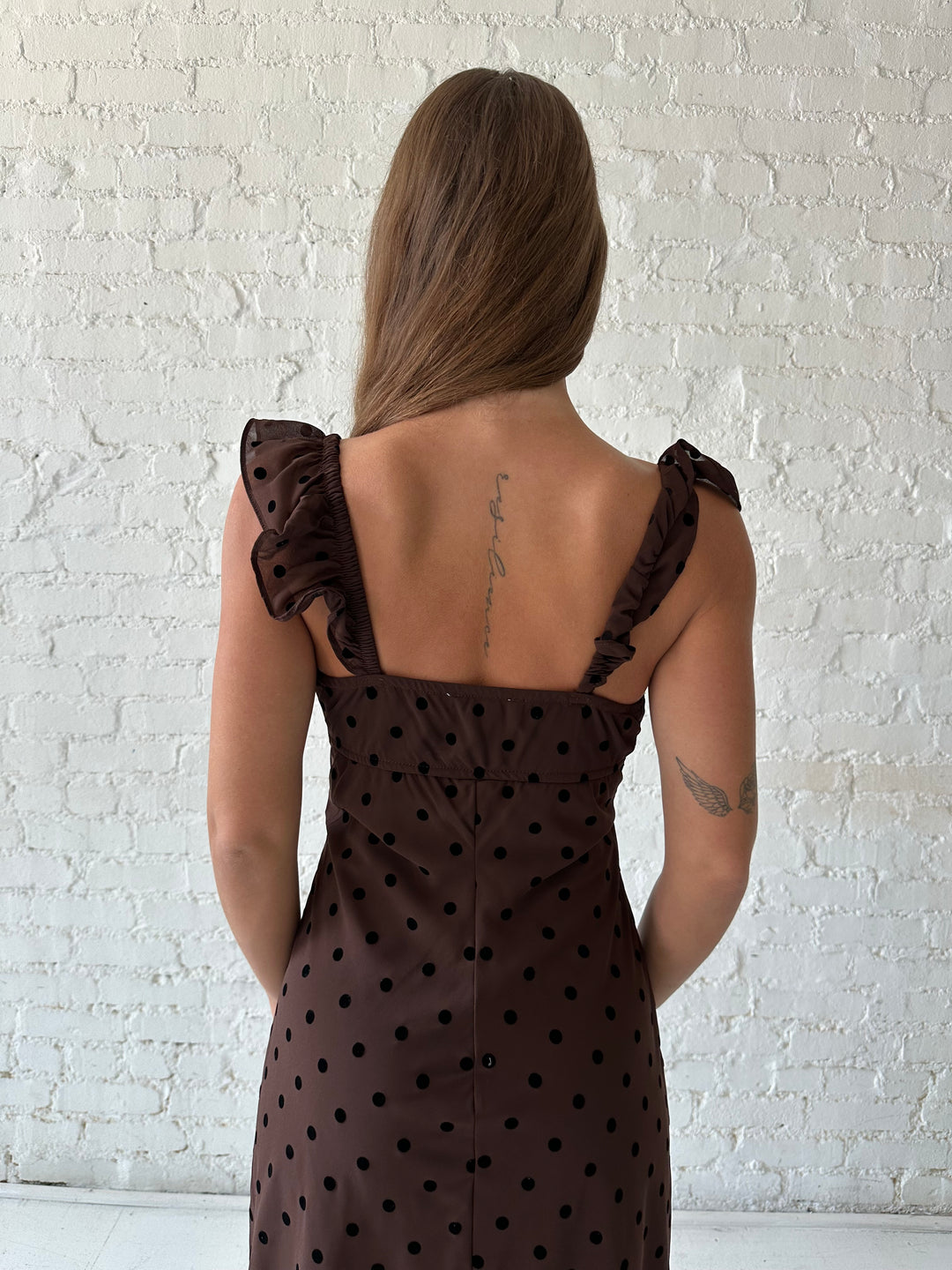 Woman wearing brown polka dot midi dress with ruffle straps.