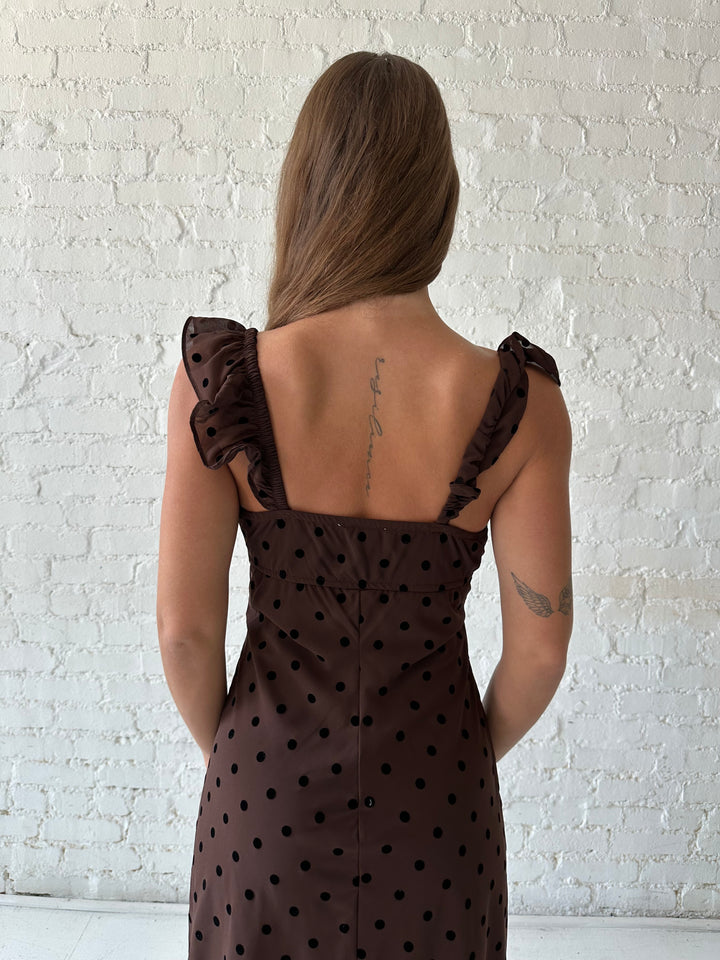 Woman wearing brown polka dot midi dress with ruffle straps.