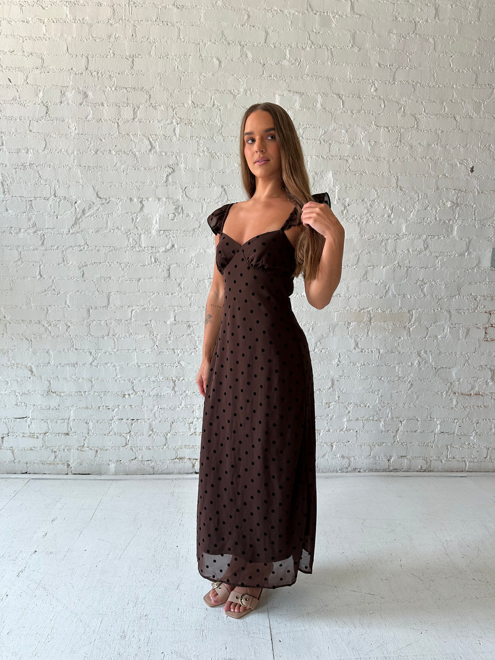 Woman wearing brown polka dot midi dress with ruffle straps.