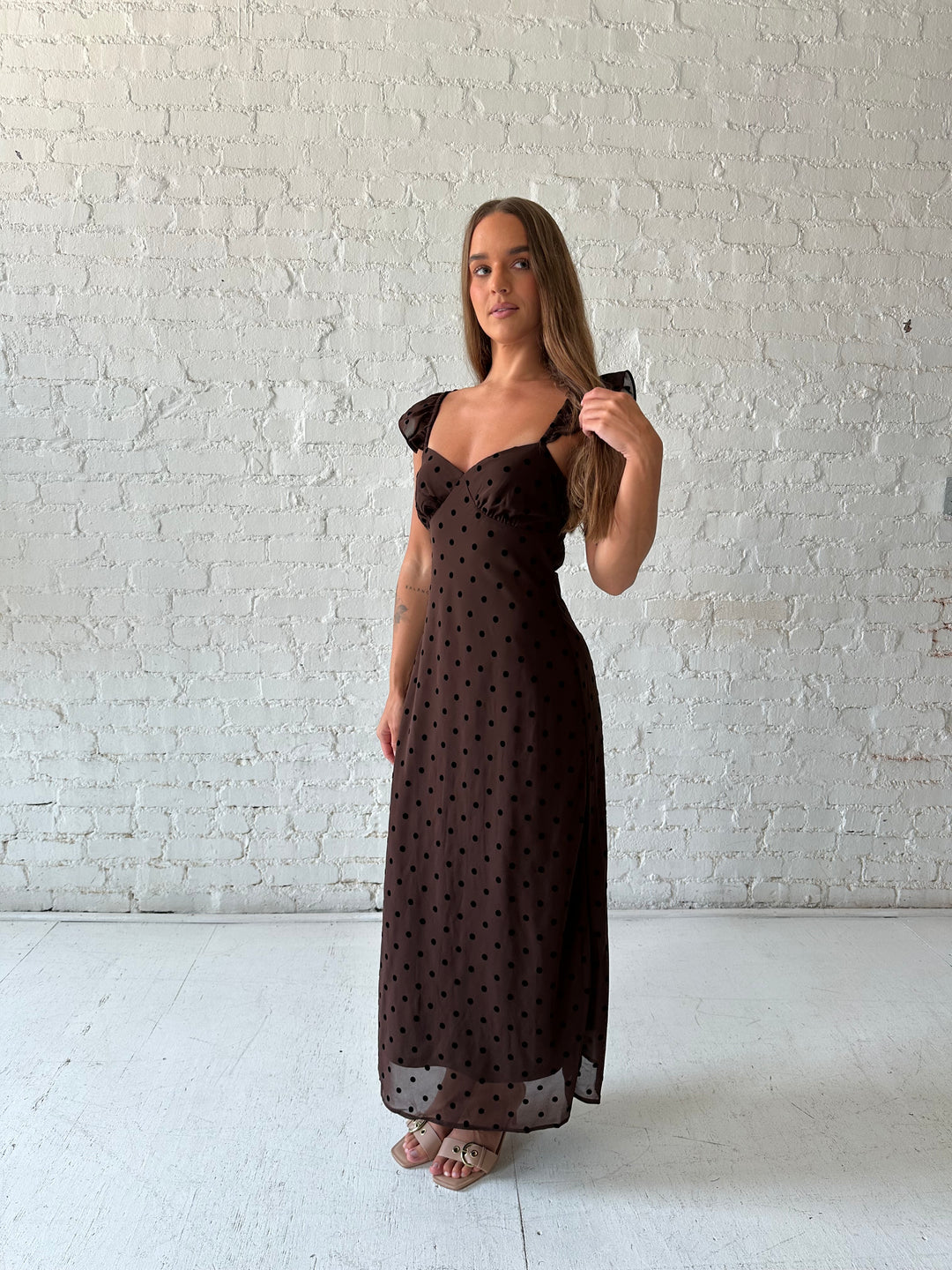 Woman wearing brown polka dot midi dress with ruffle straps.