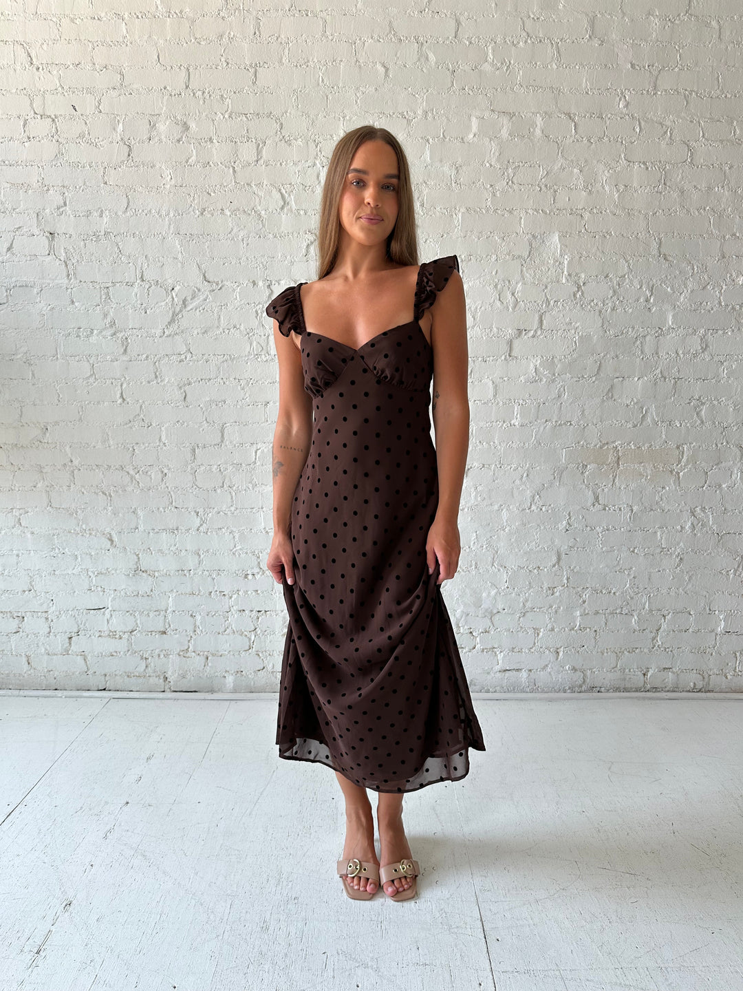 Woman wearing brown polka dot midi dress with ruffle straps.