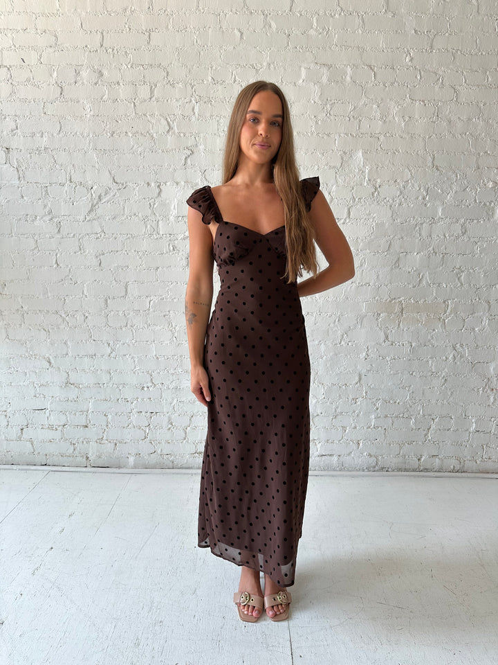Woman wearing brown polka dot midi dress with ruffle straps.