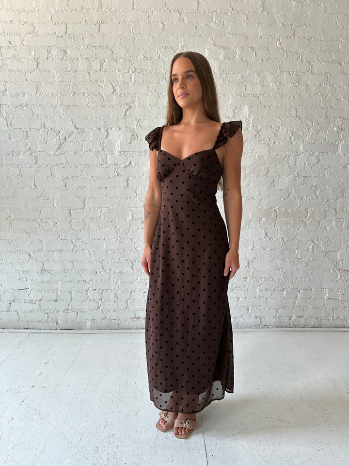 Woman wearing brown polka dot midi dress with ruffle straps.