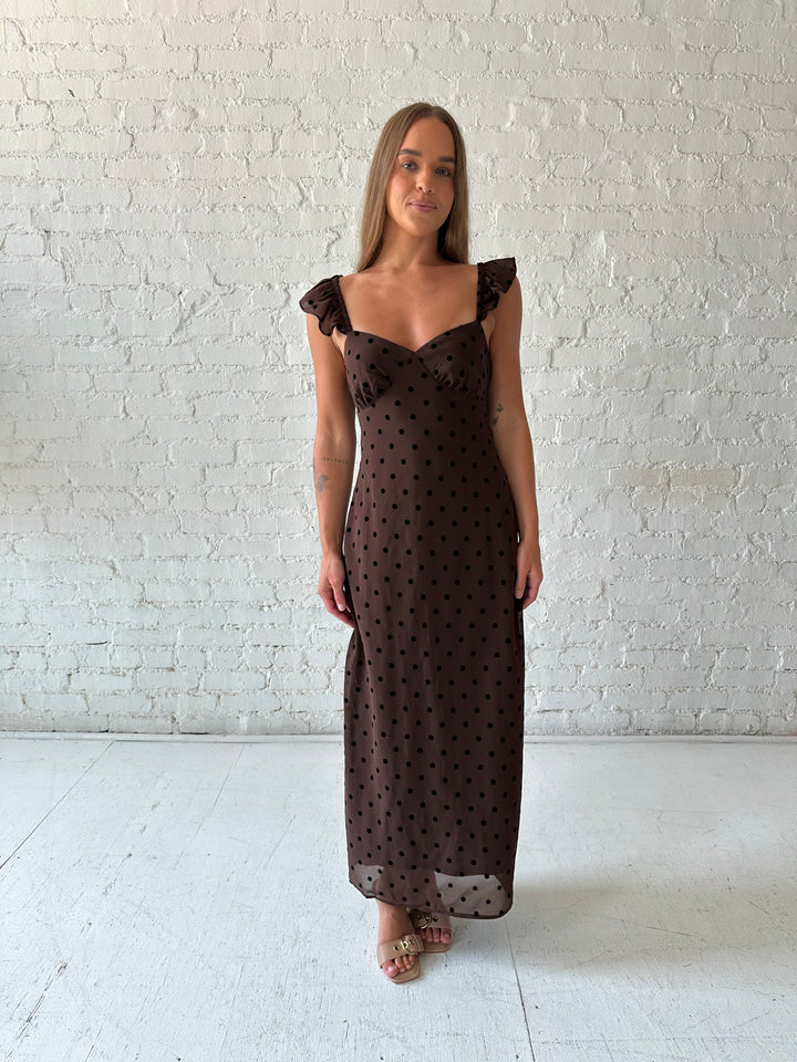 Woman wearing brown polka dot midi dress with ruffle straps.