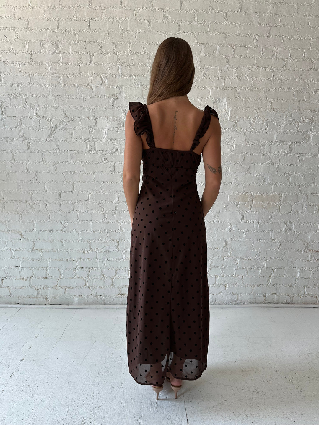 Woman wearing brown polka dot midi dress with ruffle straps.