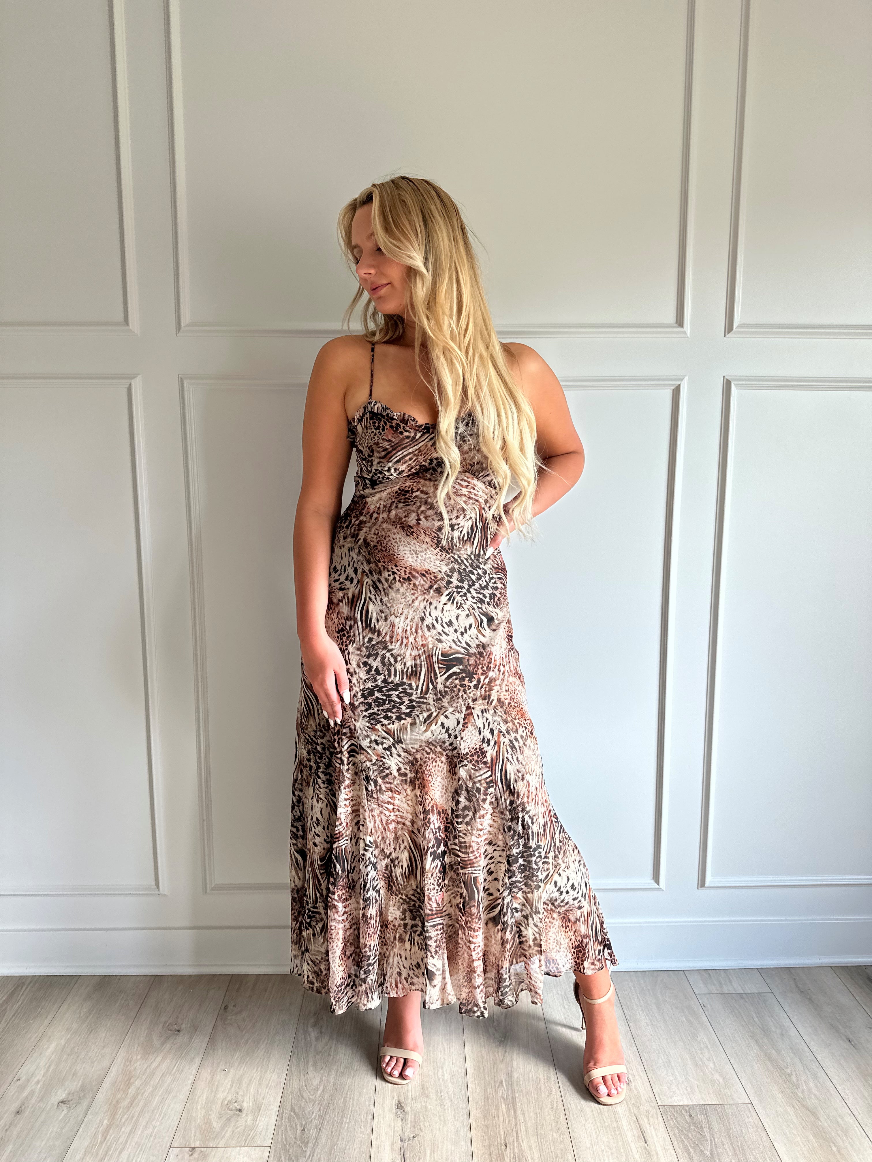 Woman wearing a leopard print maxi dress with adjustable spaghetti straps. 