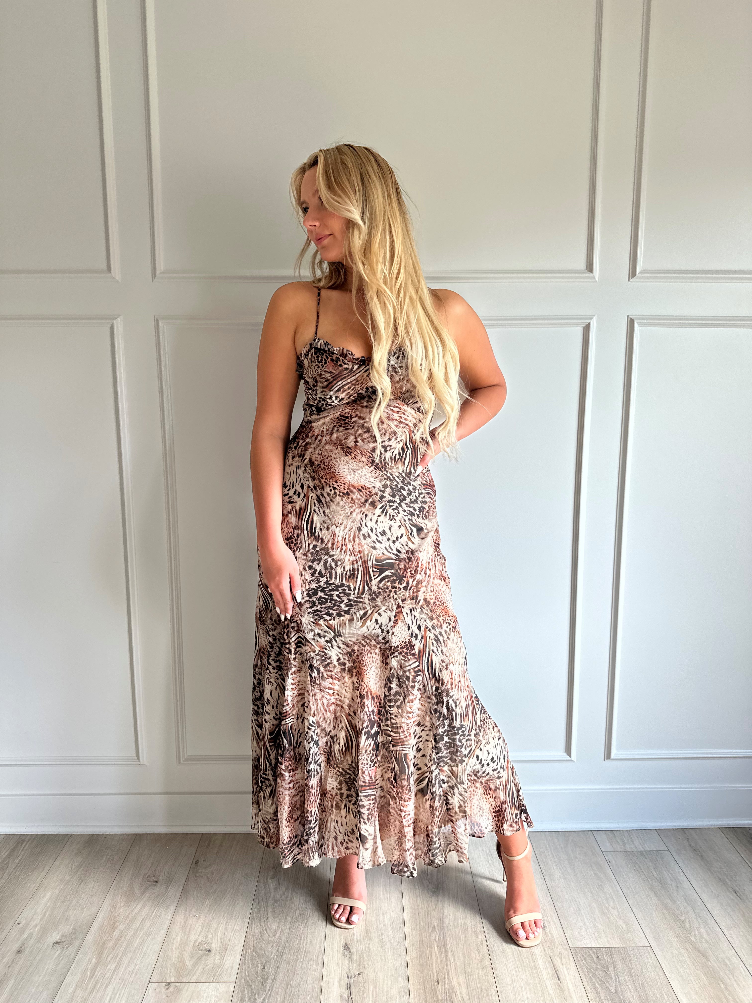 Woman wearing a leopard print maxi dress with adjustable spaghetti straps. 
