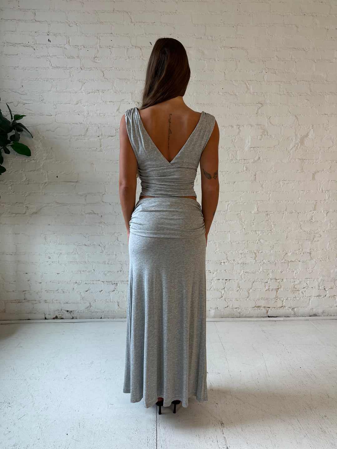 Woman wearing grey two piece set with v-neckline top and long fold over maxi skirt. 