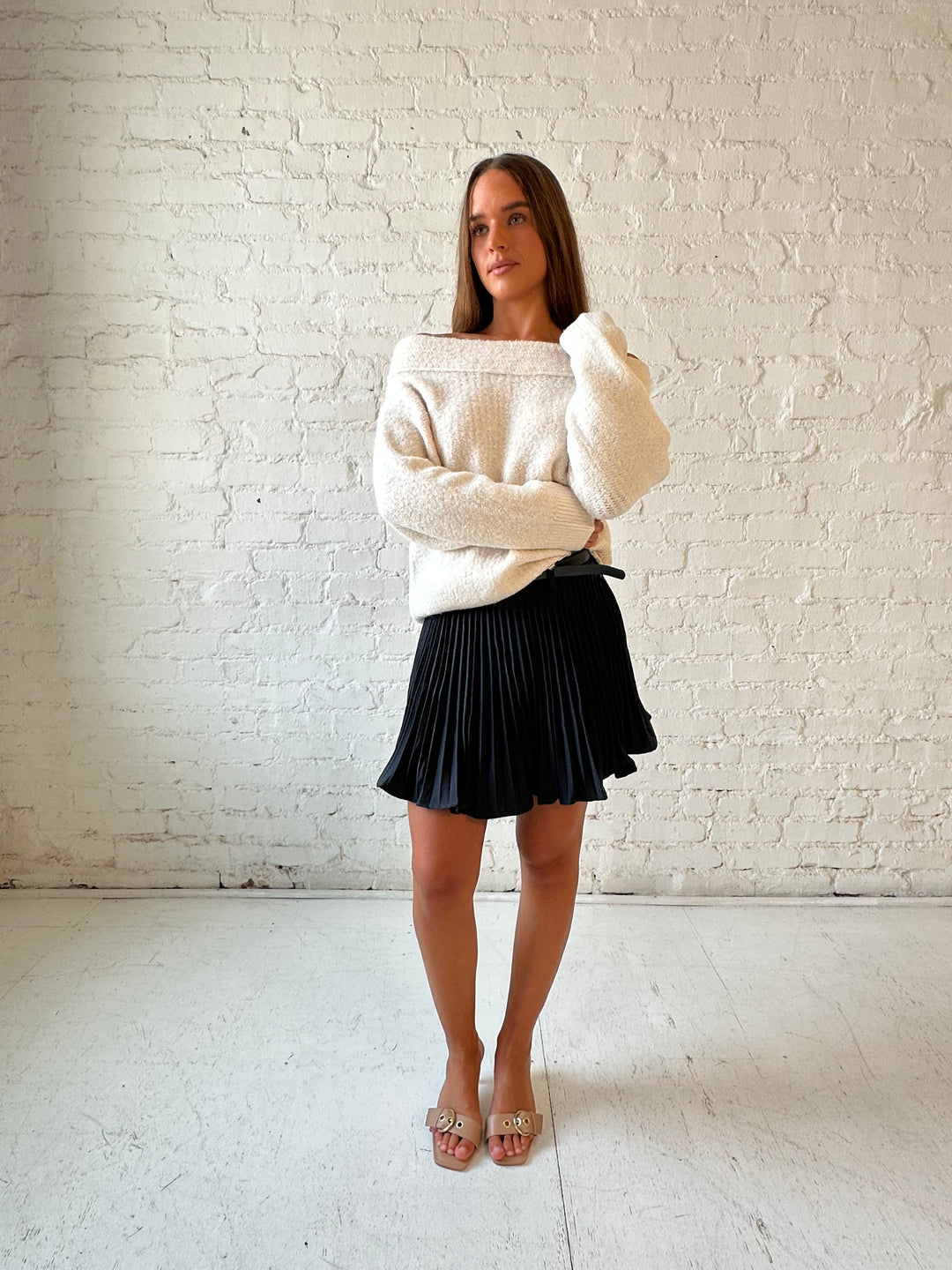 Woman wearing charcoal gray pleated mini skort with cream off the shoulder sweater. 