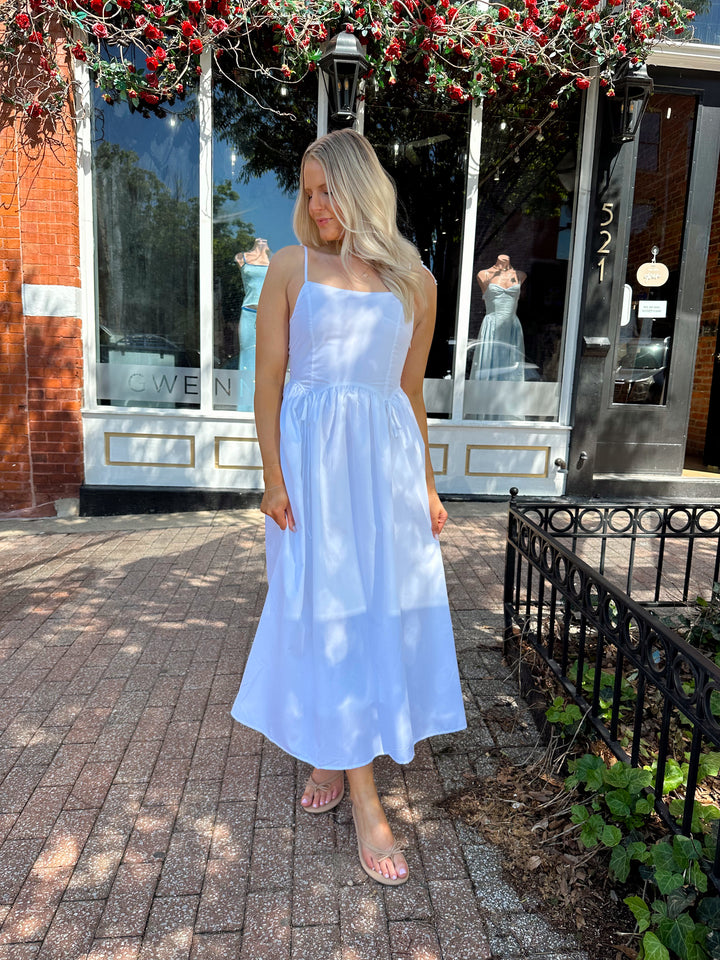 Woman wearing white midi dress with front tie detail, and self tie straps.