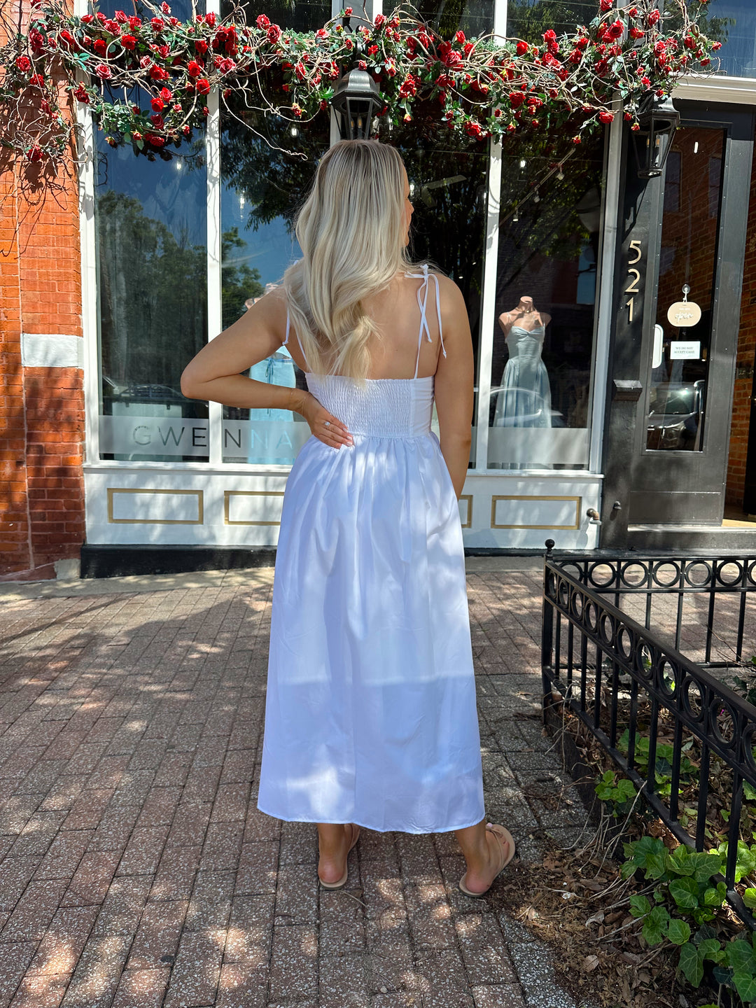 Woman wearing white midi dress with front tie detail, and self tie straps.