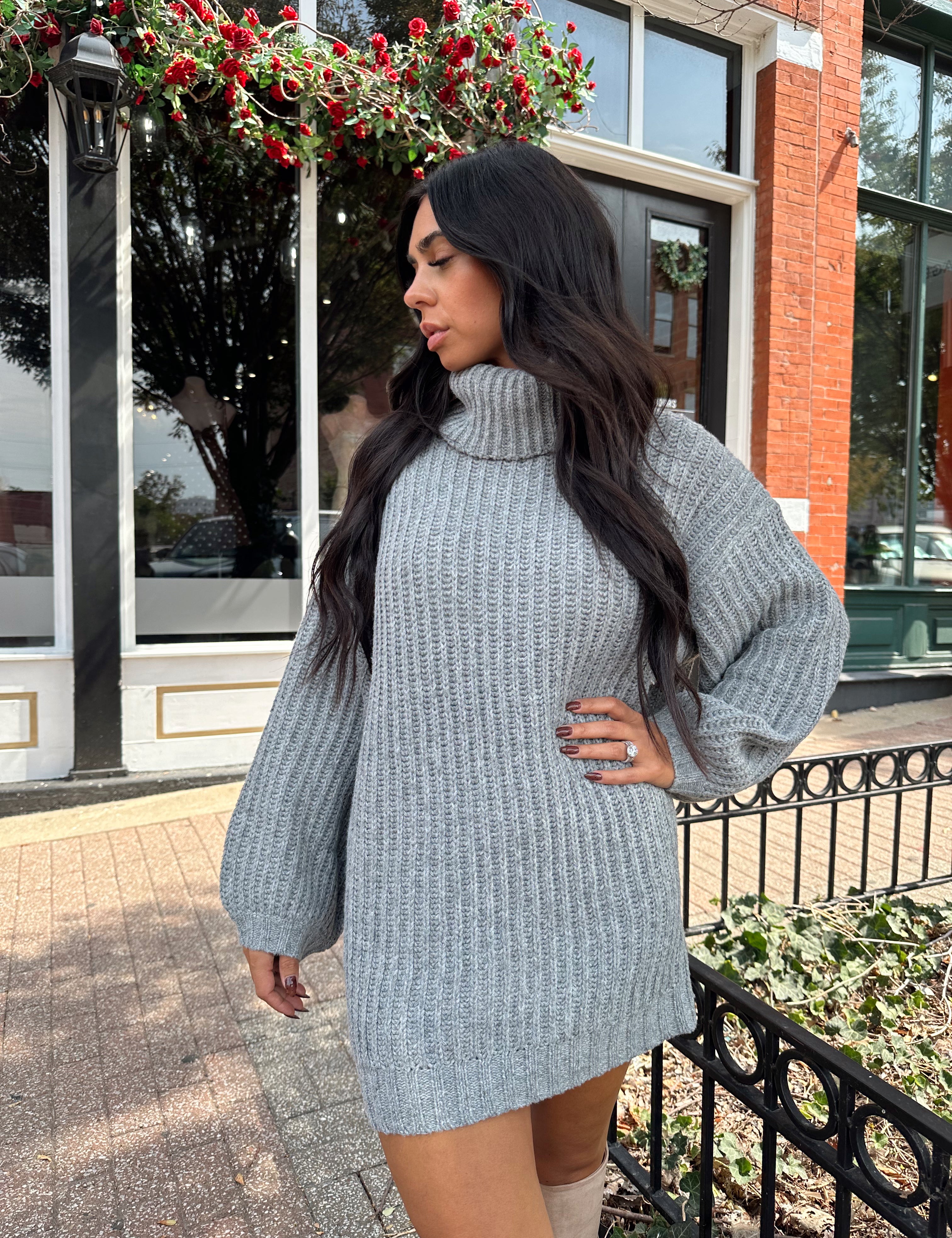 Woman wearing grey knit oversized turtle neck sweater dress with suede knee boots.