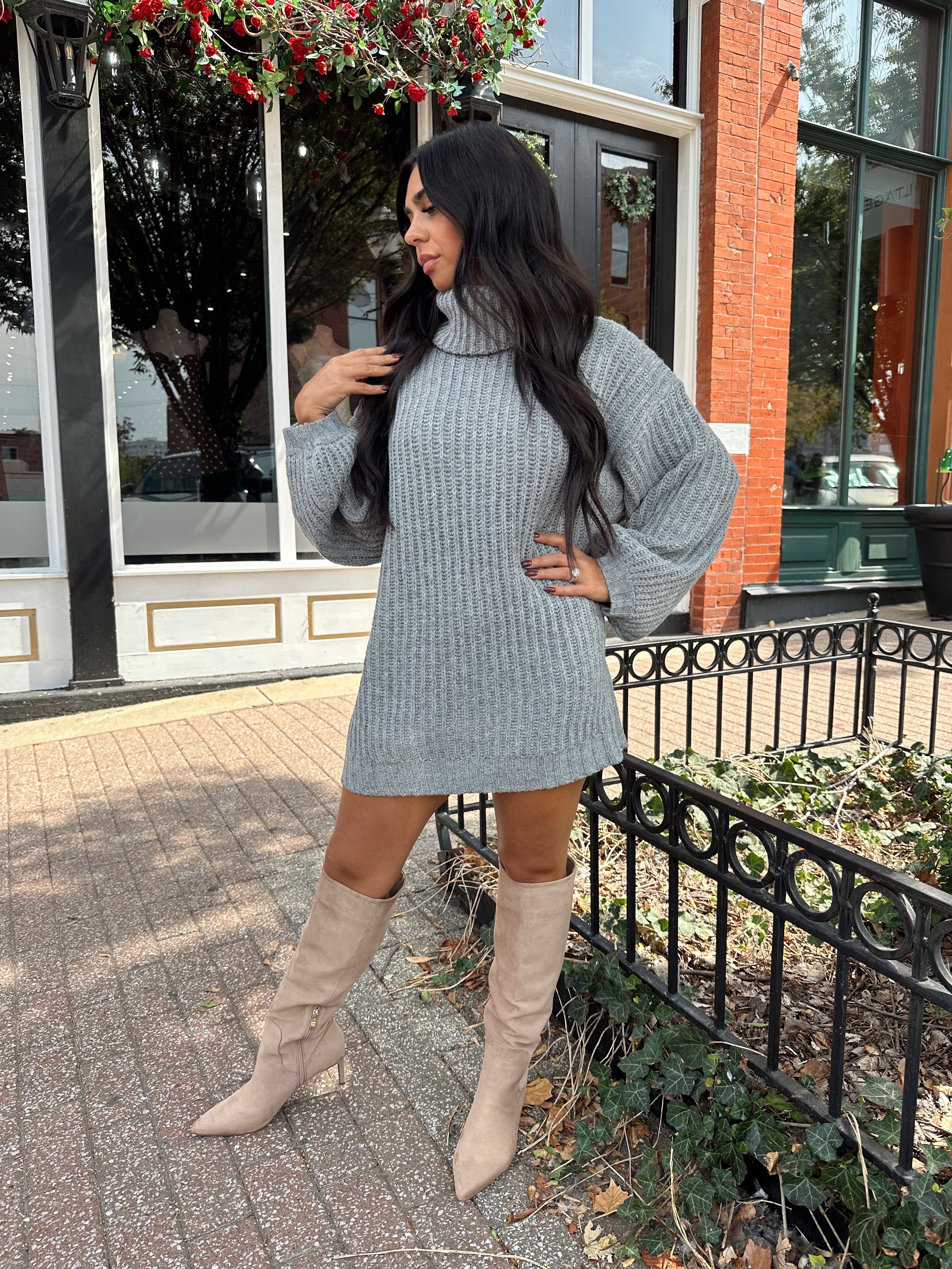 Woman wearing grey knit oversized turtle neck sweater dress with suede knee boots.
