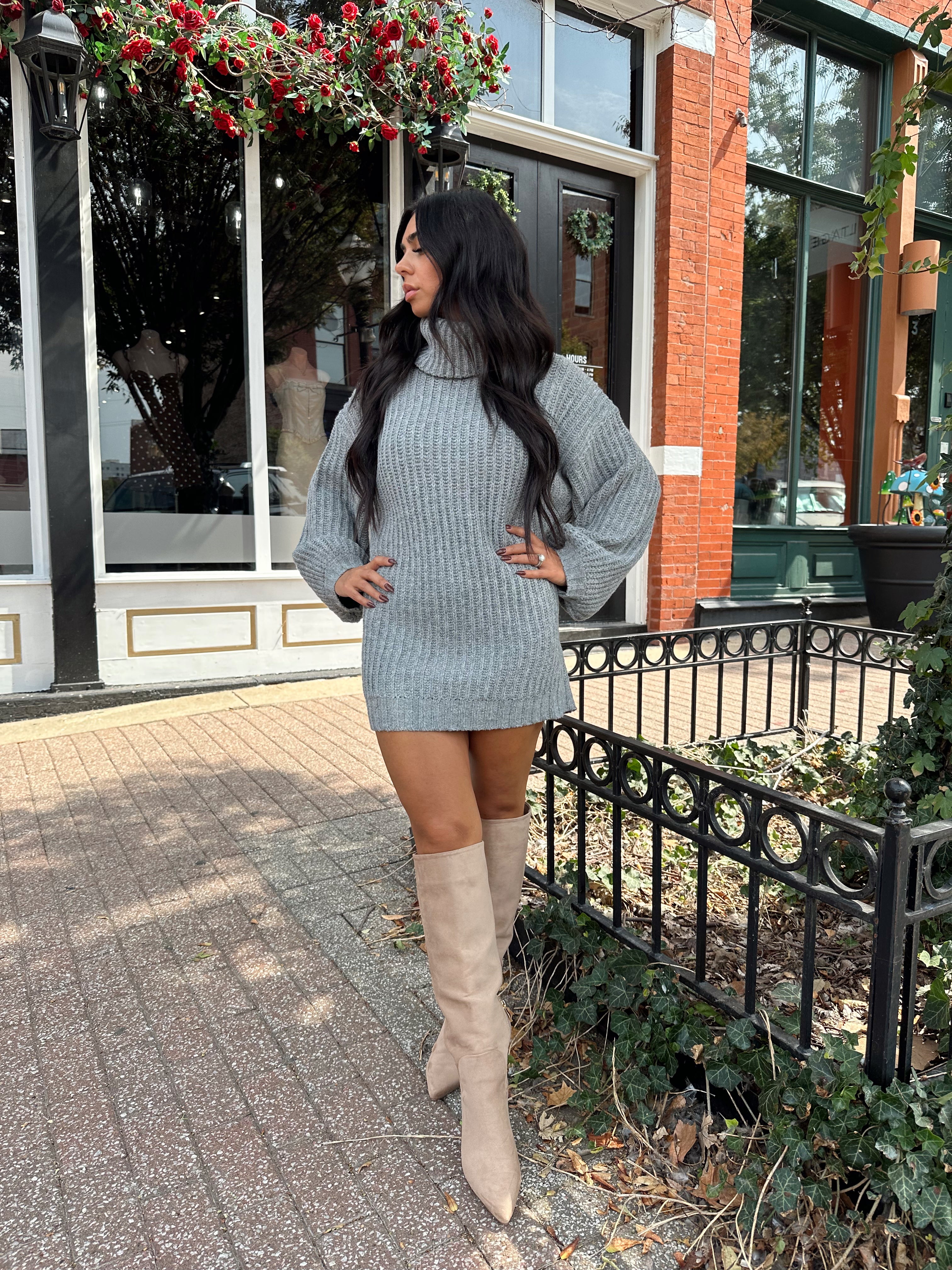 Woman wearing grey knit oversized turtle neck sweater dress with suede knee boots.