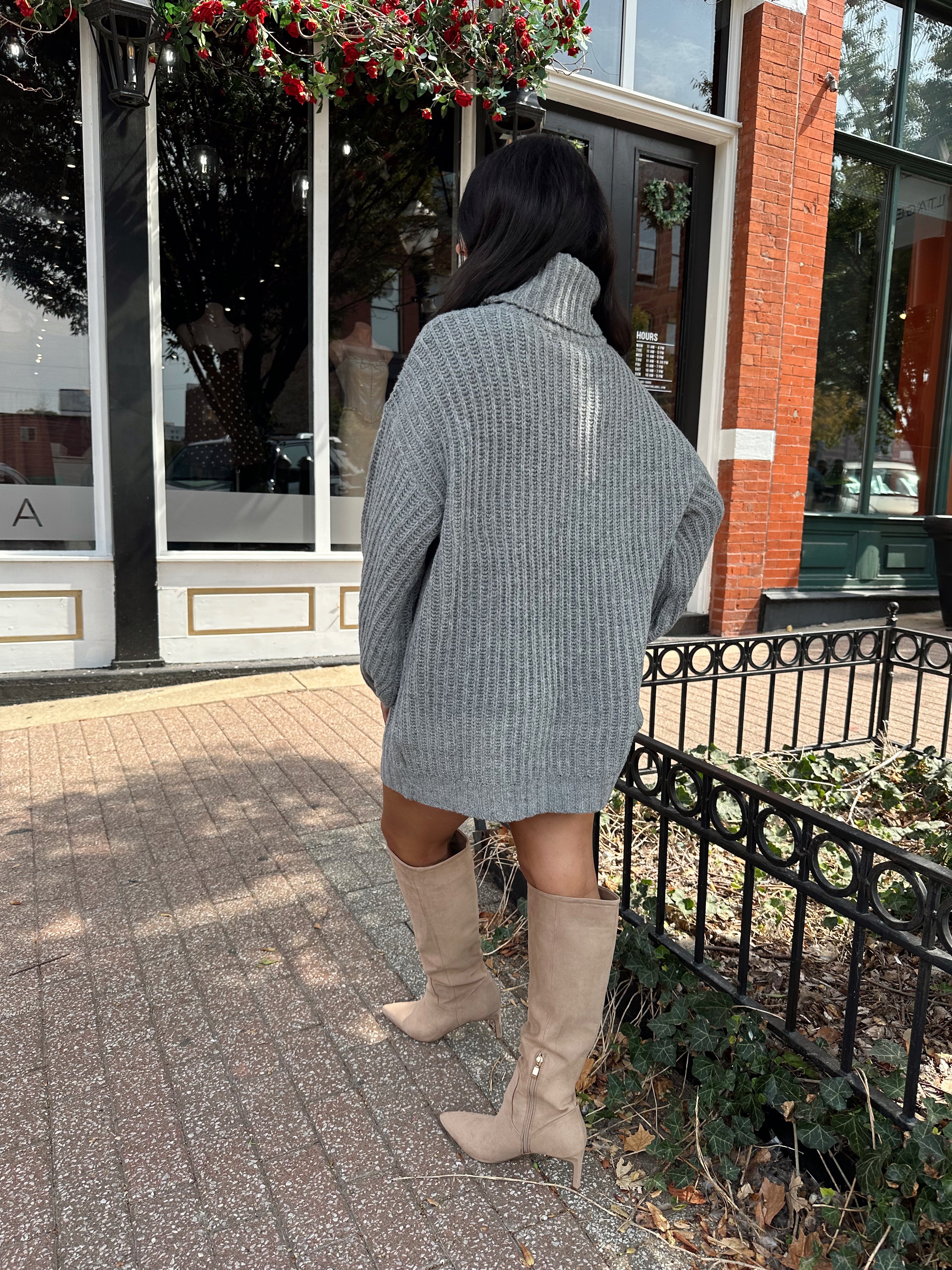 Woman wearing grey knit oversized turtle neck sweater dress with suede knee boots.