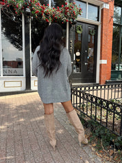 Woman wearing grey knit oversized turtle neck sweater dress with suede knee boots.