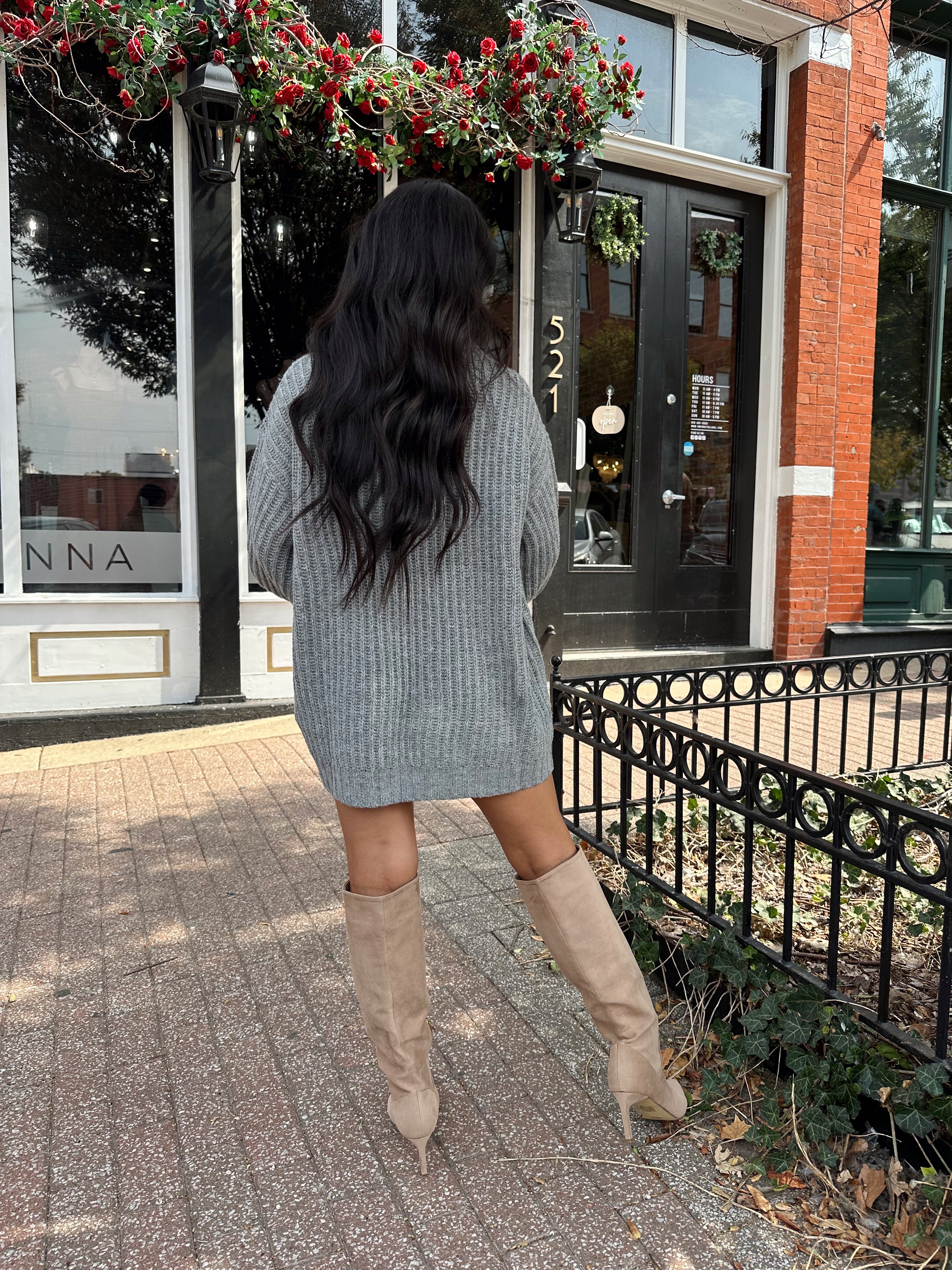 Woman wearing grey knit oversized turtle neck sweater dress with suede knee boots.