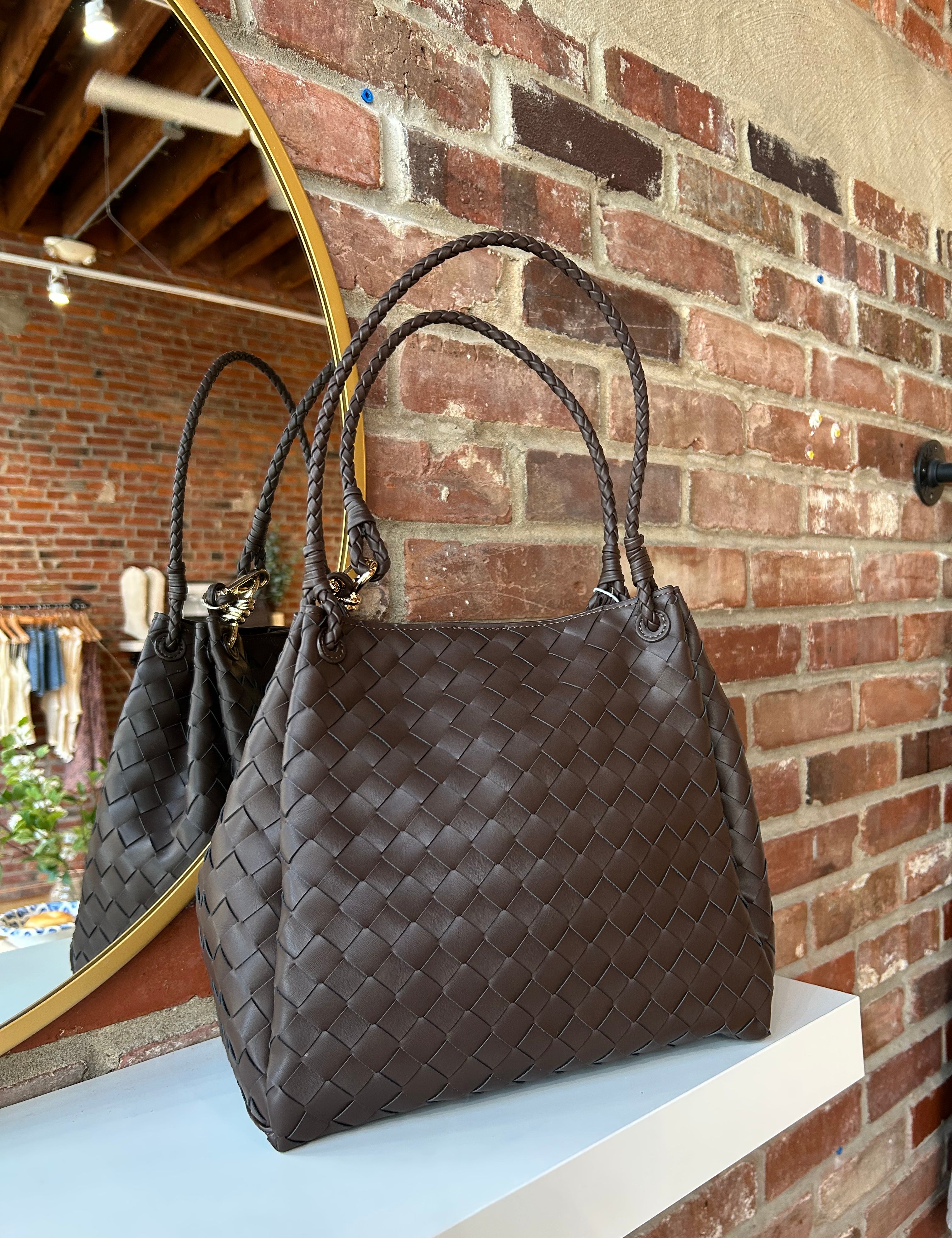 Dark brown vegan leather woven shoulder bag with braided straps and gold hardware. 