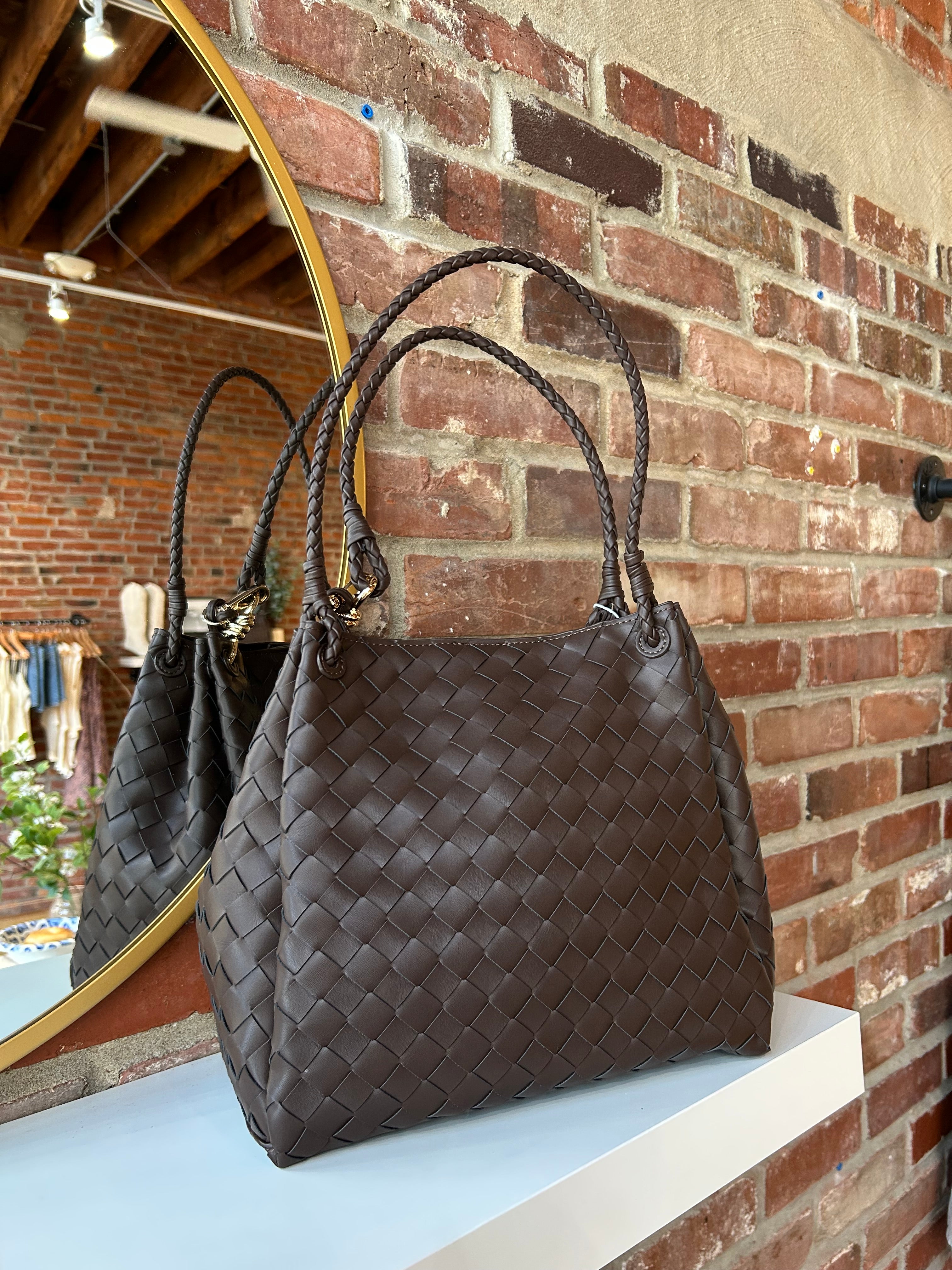 Dark brown vegan leather woven shoulder bag with braided straps and gold hardware. 