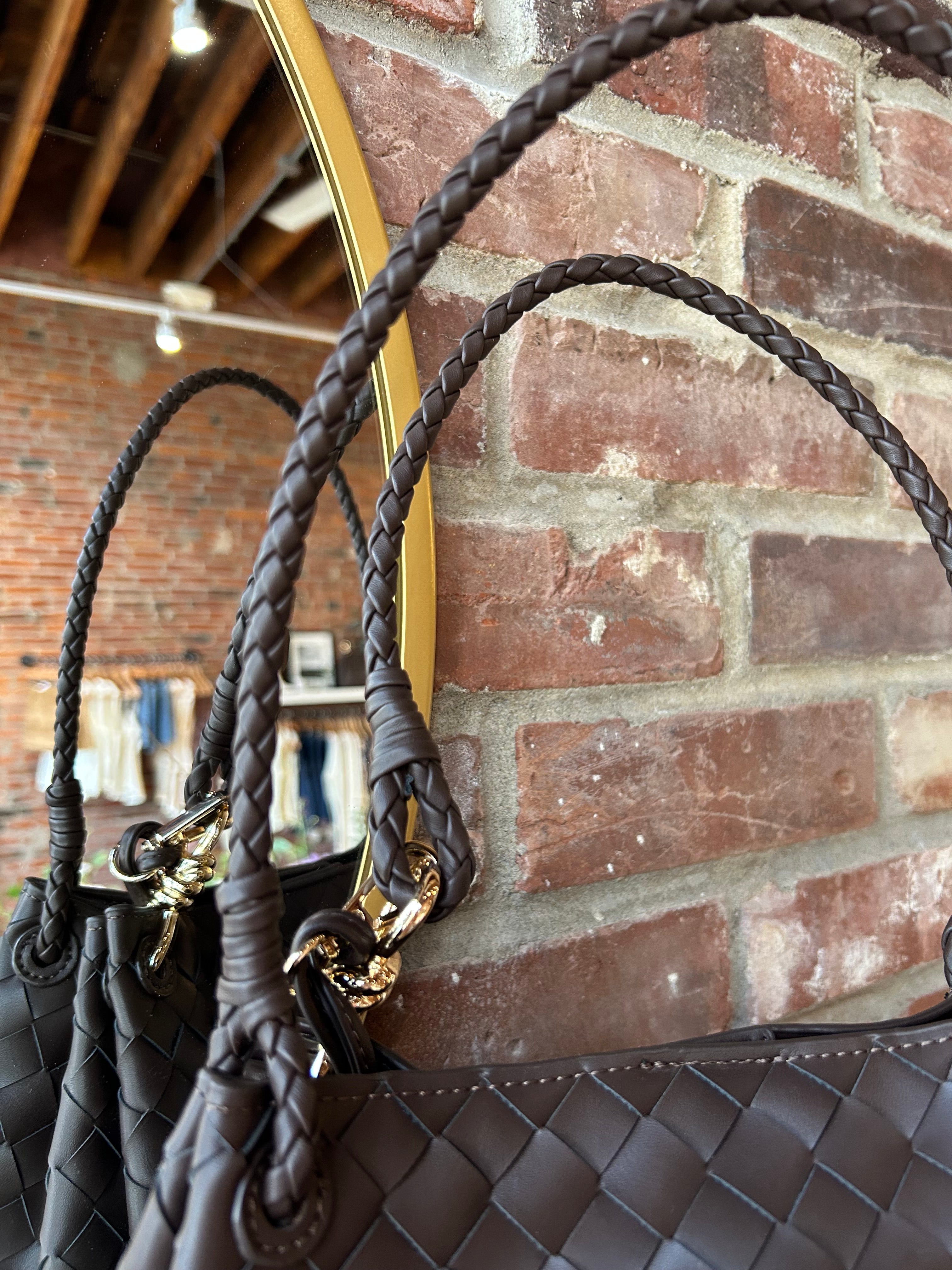 Dark brown vegan leather woven shoulder bag with braided straps and gold hardware. 