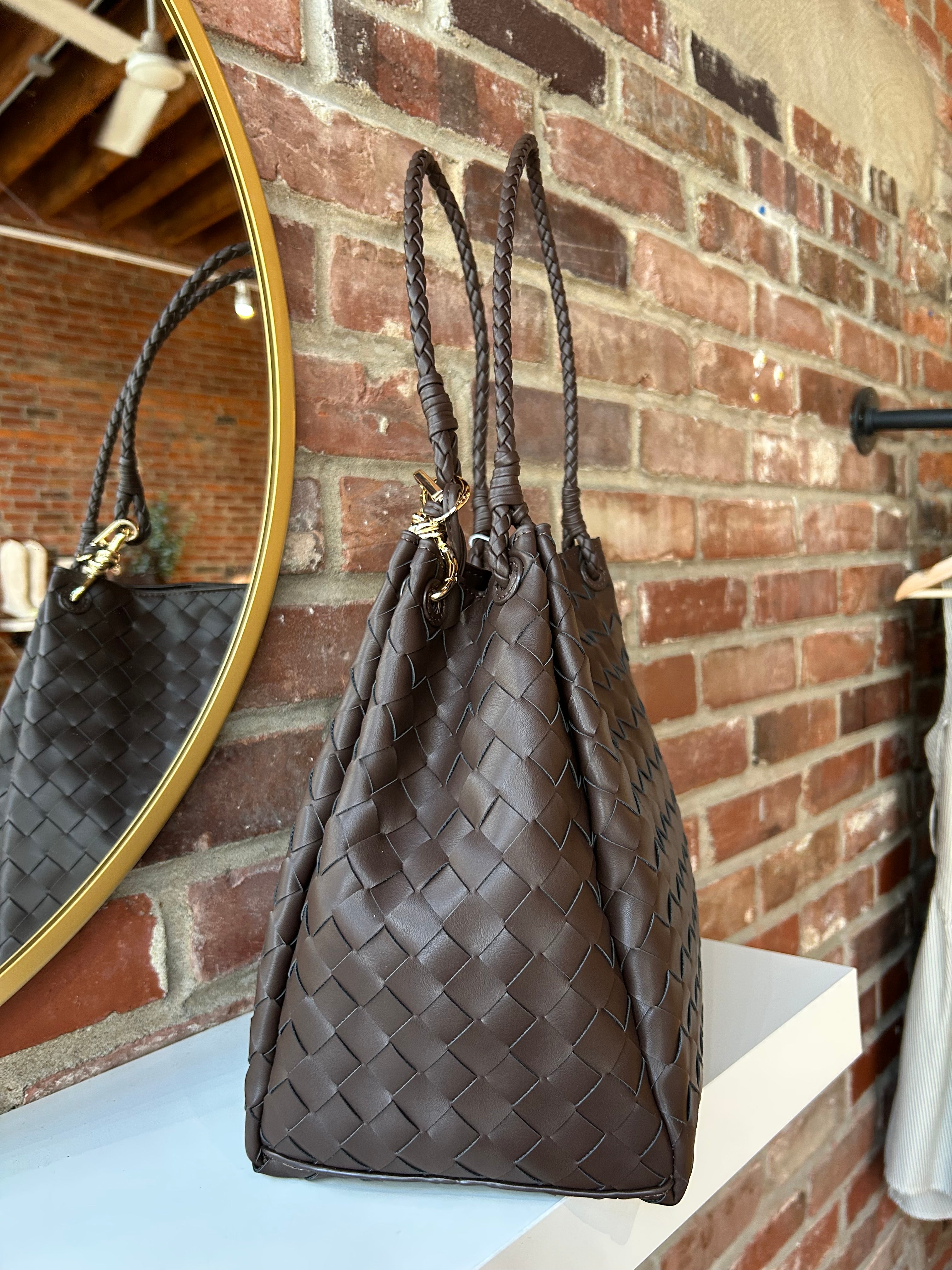 Dark brown vegan leather woven shoulder bag with braided straps and gold hardware. 