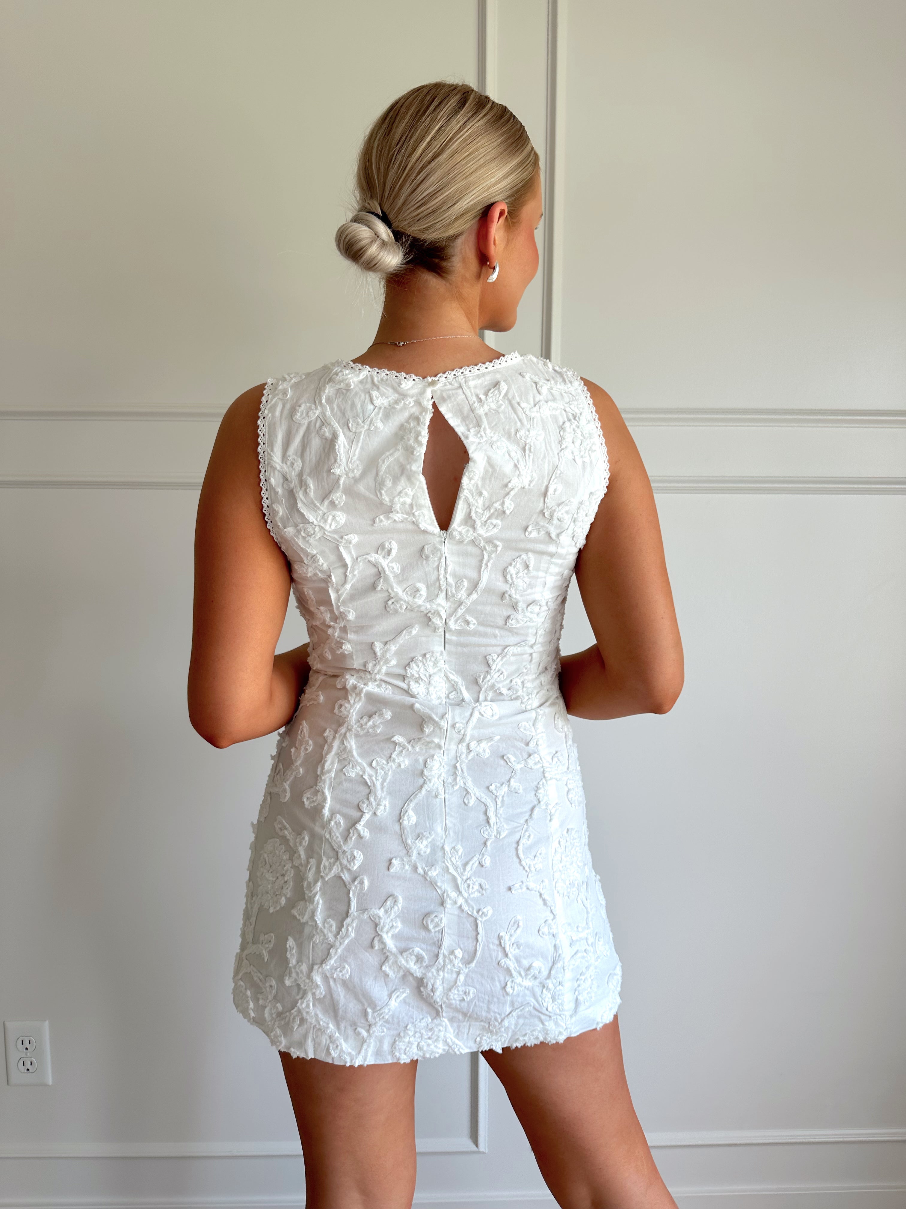 White a-line mini dress with floral jacquard pattern.