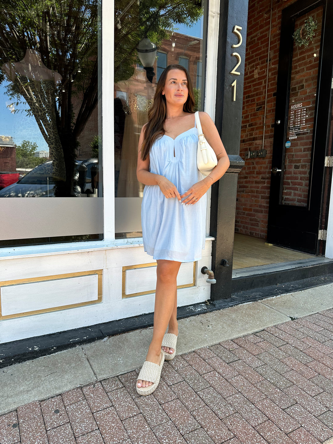 Woman wearing light blue mini dress with keyhole cutout, and adjustable straps. 