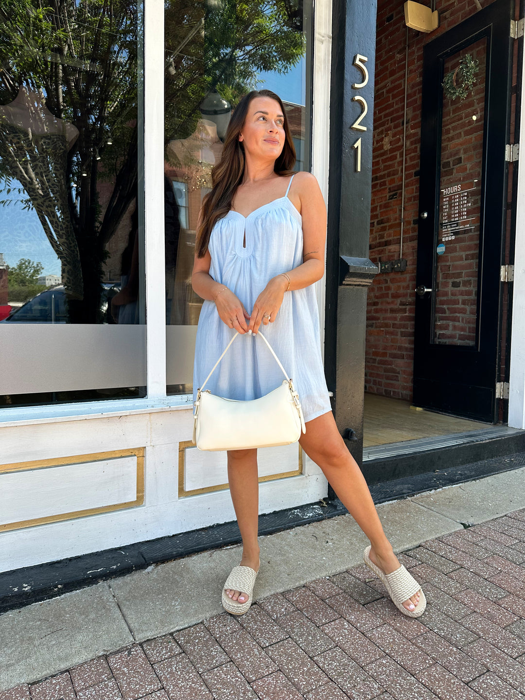 Woman wearing light blue mini dress with keyhole cutout, and adjustable straps. 