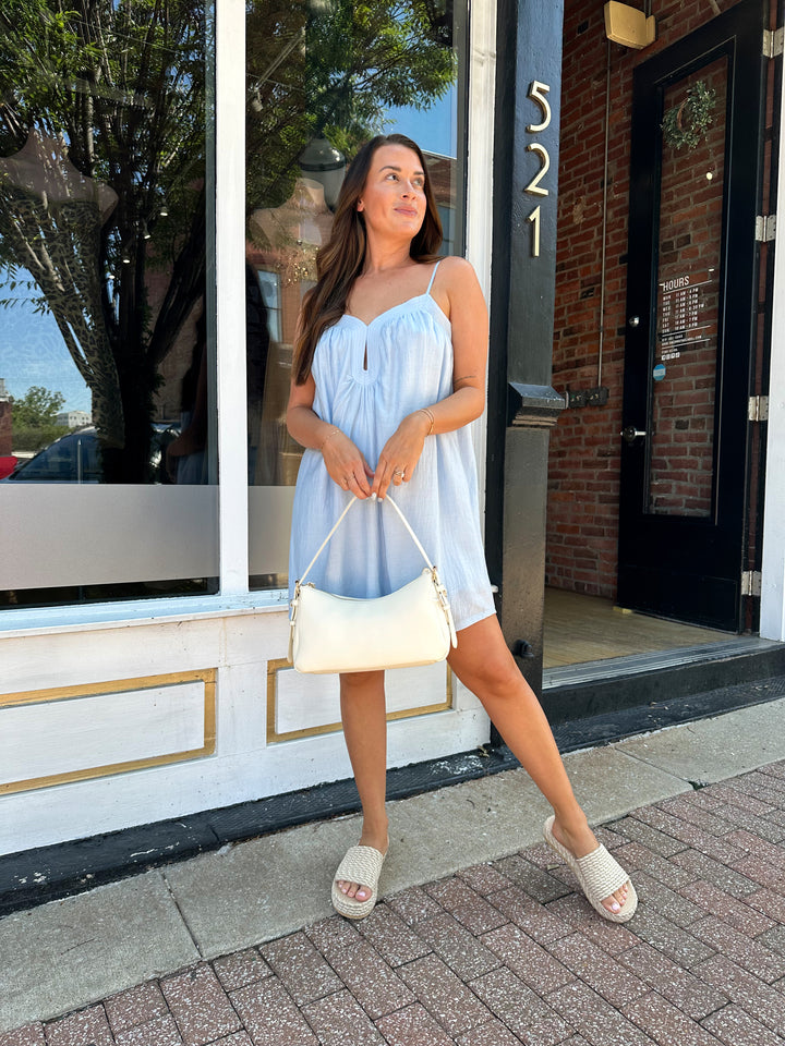 Woman wearing light blue mini dress with keyhole cutout, and adjustable straps. 