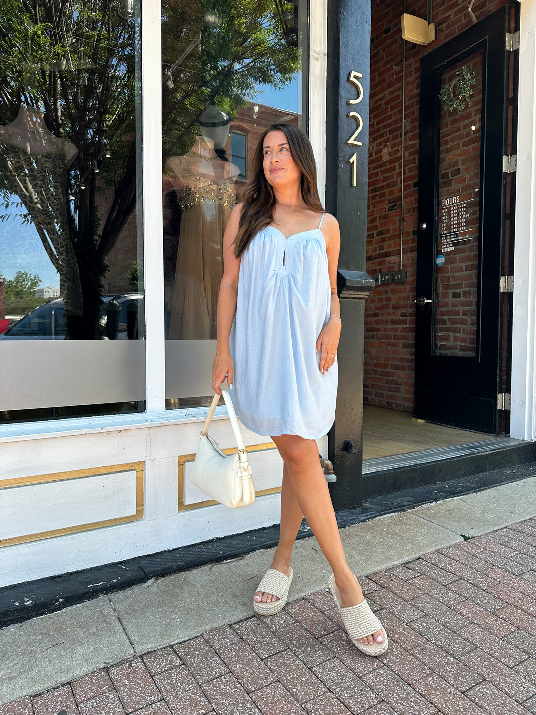 Woman wearing light blue mini dress with keyhole cutout, and adjustable straps. 