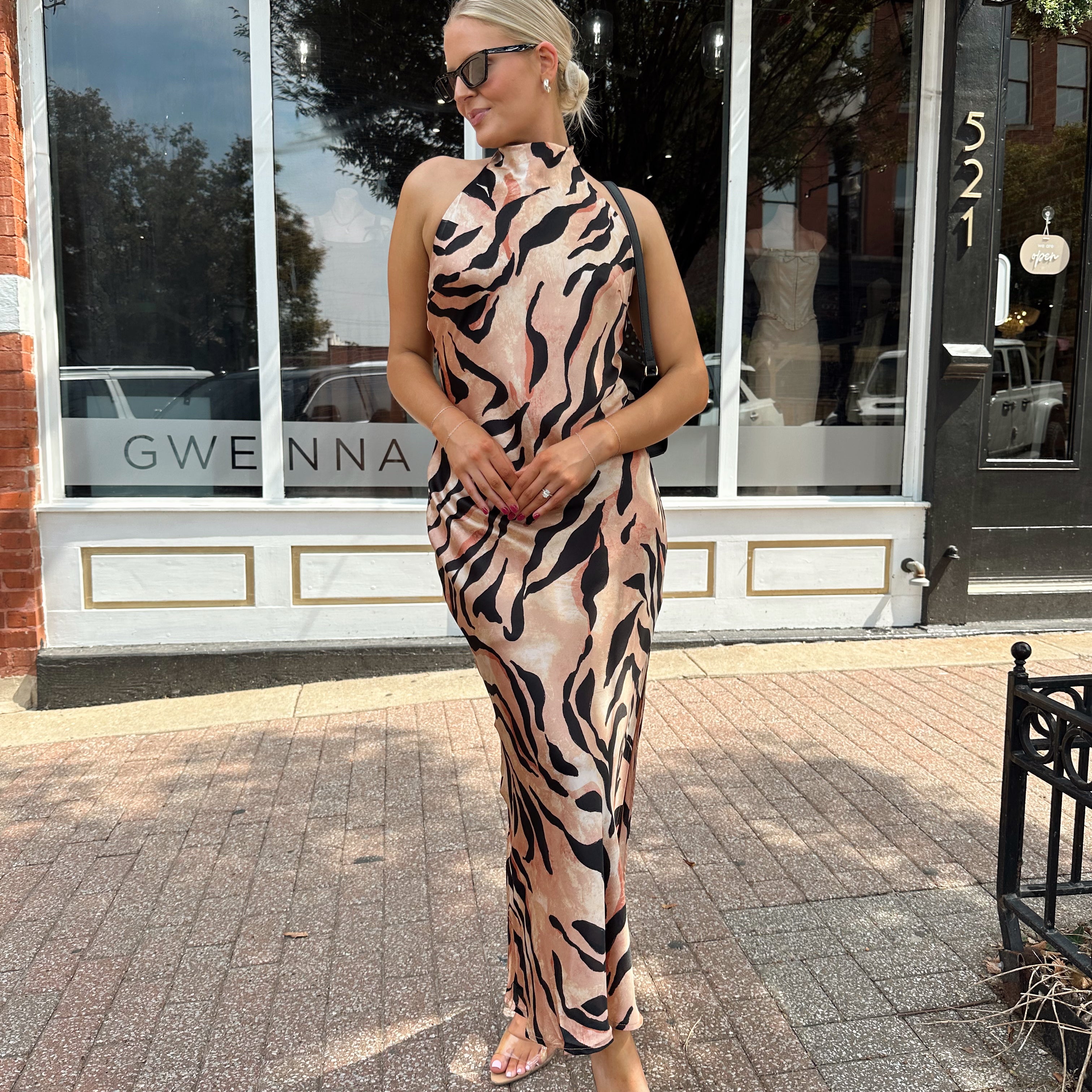Woman wearing tiger print high neck maxi dress with open back and slit up the side.