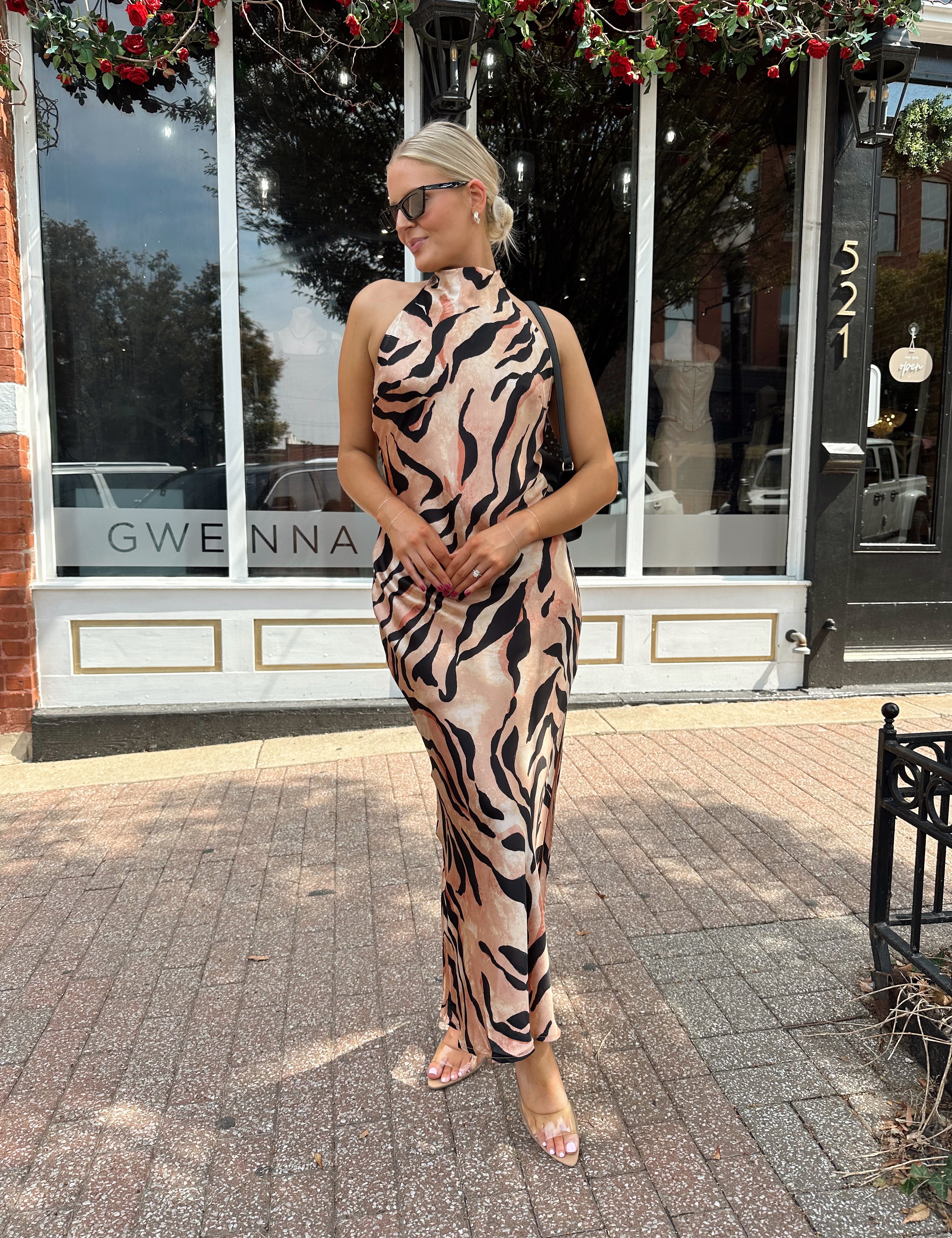 Woman wearing tiger print high neck maxi dress with open back and slit up the side.