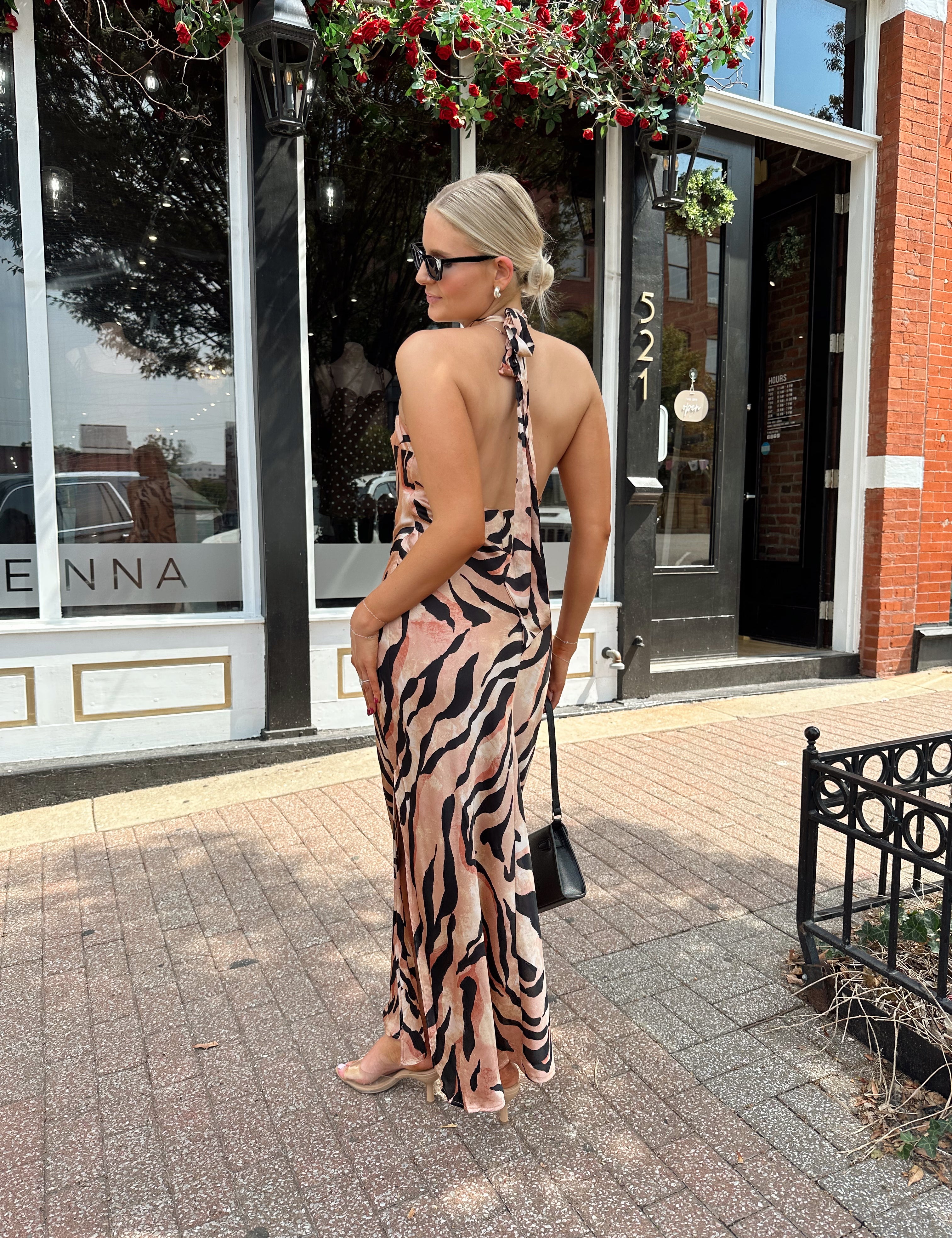 Woman wearing tiger print high neck maxi dress with open back and slit up the side.