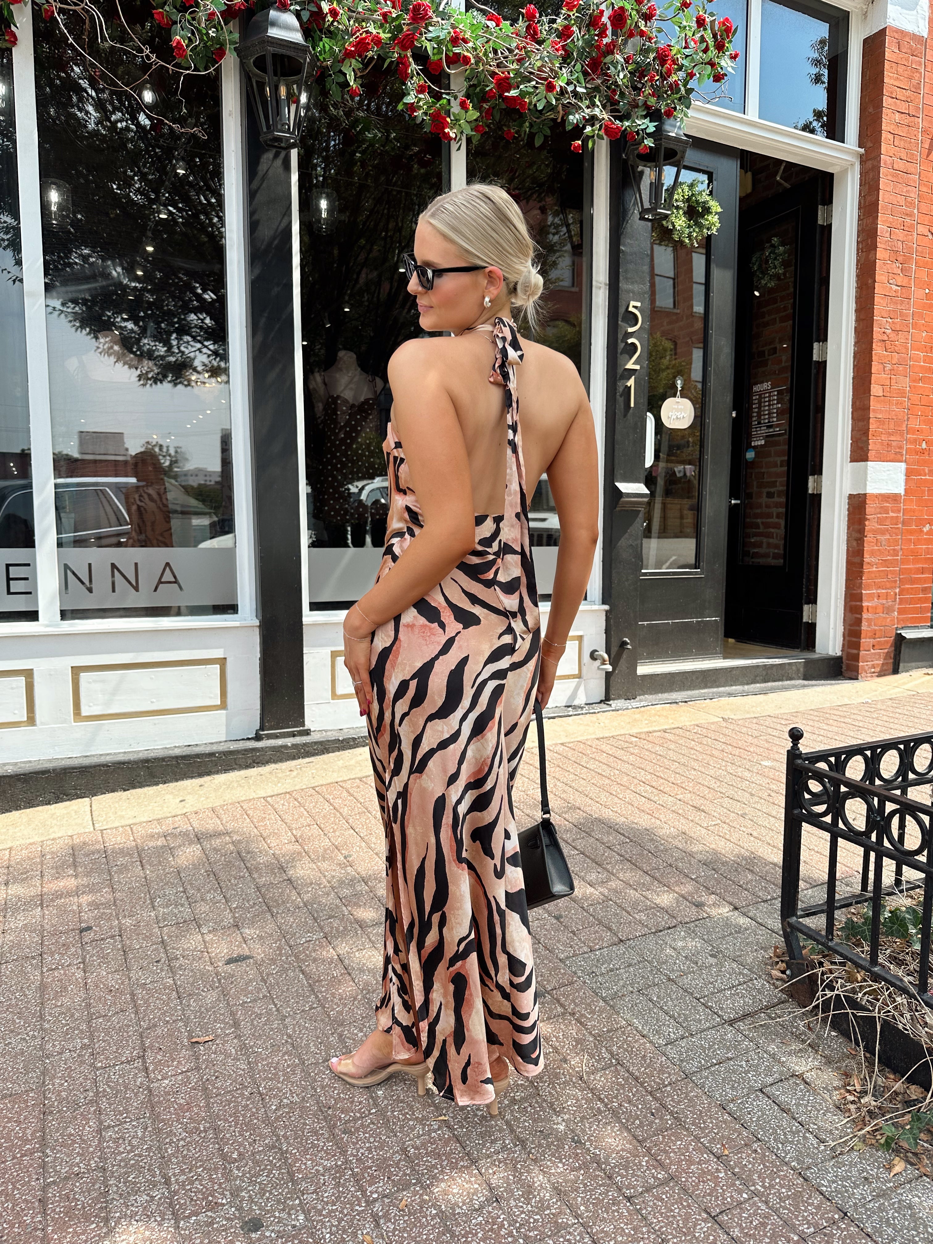 Woman wearing tiger print high neck maxi dress with open back and slit up the side.