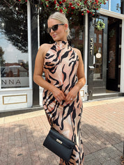 Woman wearing tiger print high neck maxi dress with open back and slit up the side.