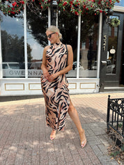 Woman wearing tiger print high neck maxi dress with open back and slit up the side.