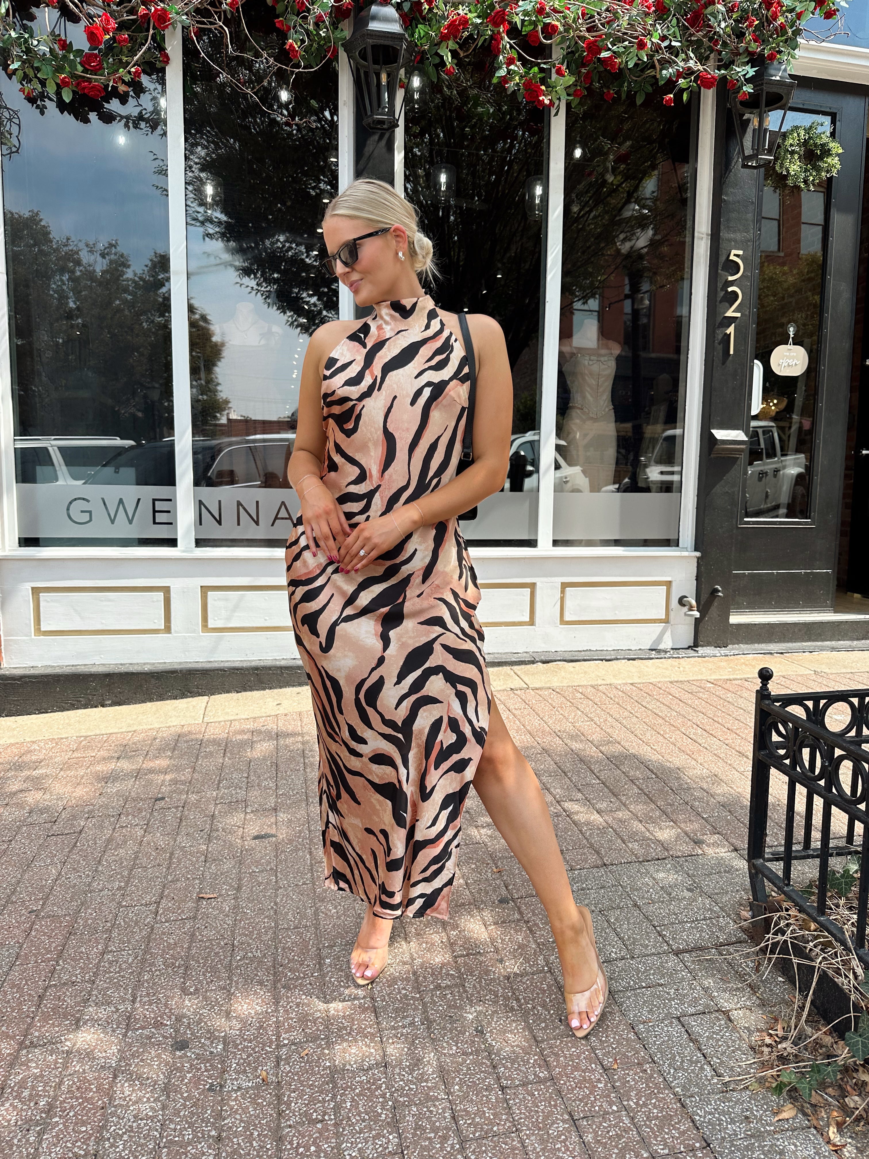 Woman wearing tiger print high neck maxi dress with open back and slit up the side.