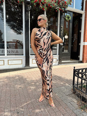 Woman wearing tiger print high neck maxi dress with open back and slit up the side.