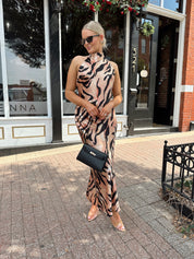 Woman wearing tiger print high neck maxi dress with open back and slit up the side.