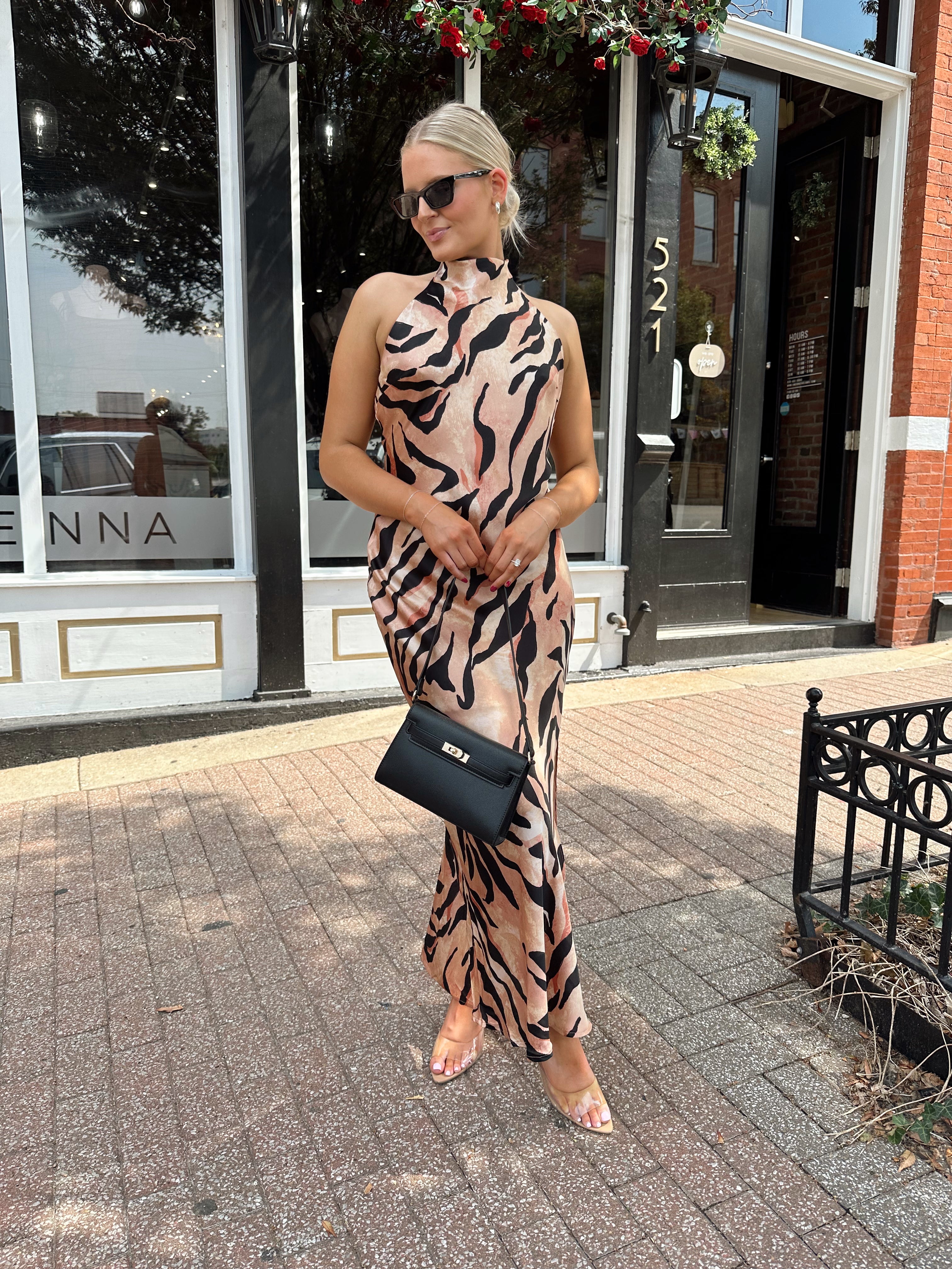 Woman wearing tiger print high neck maxi dress with open back and slit up the side.